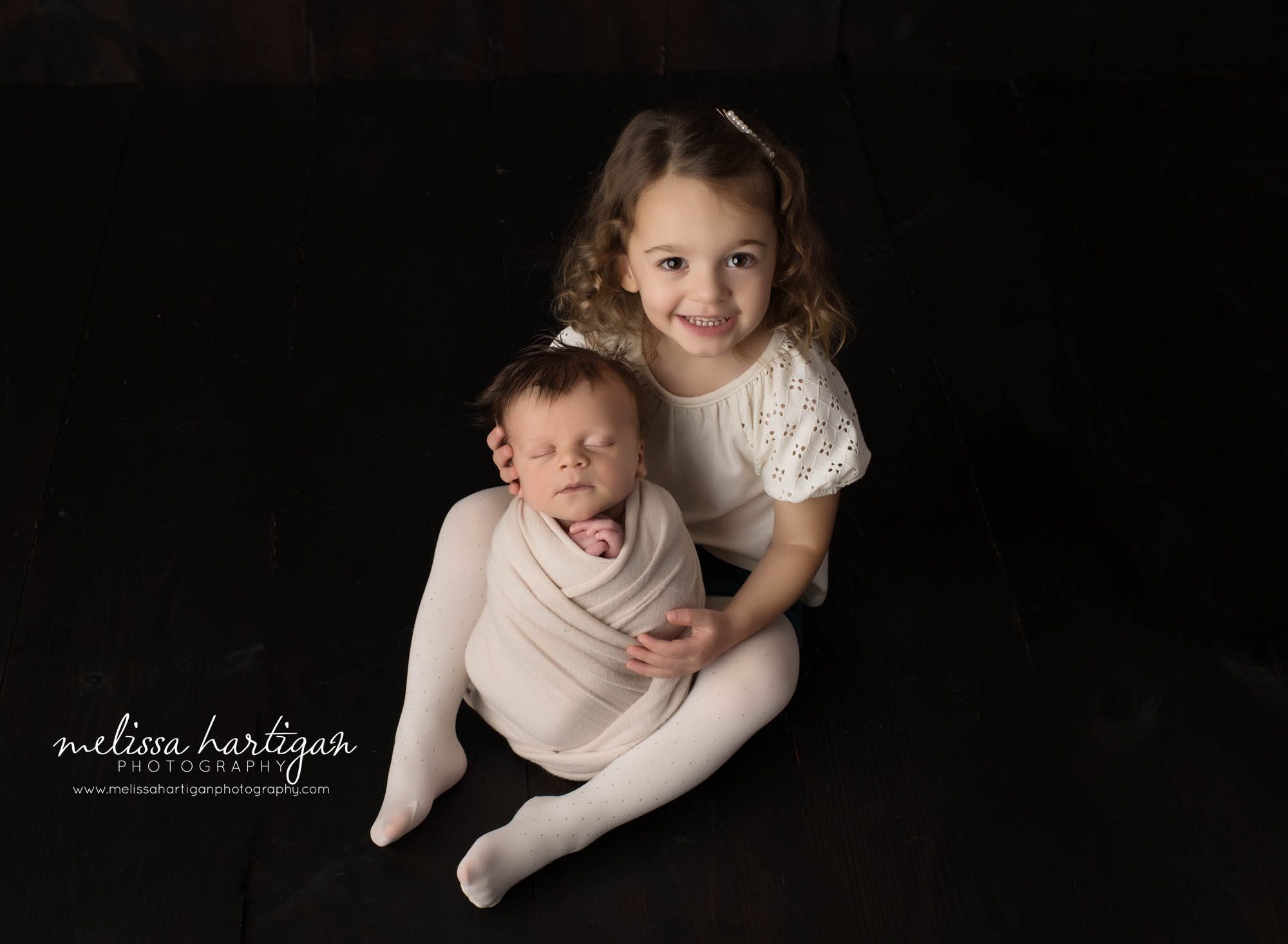 big sister holding newborn baby brother wrapped studio newborn photography photoshoot