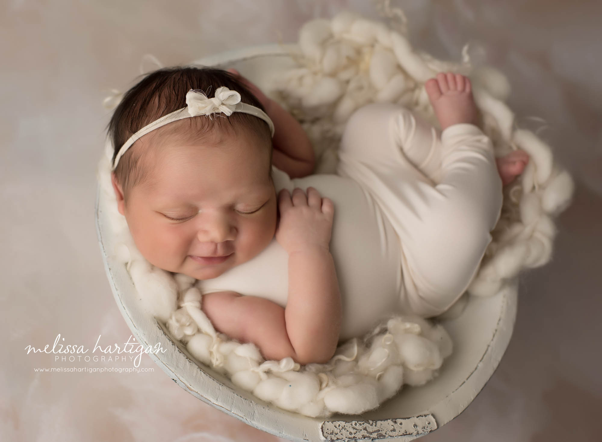 newborn baby girlk posed in wooden bowl wearing white newborn outfit and bow headband south windsor ct newborn photography