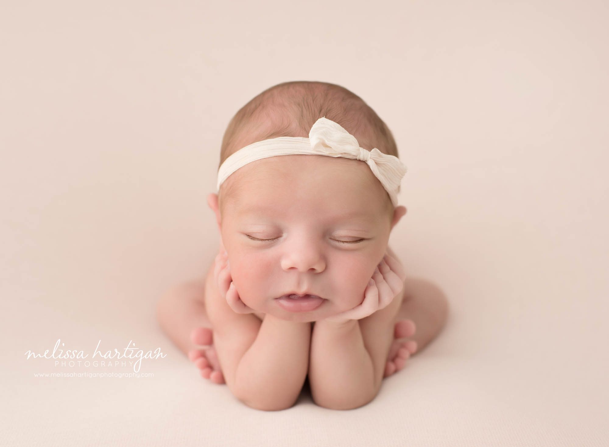 newborn baby girl posed in froggy pose on blush pink backdrop
