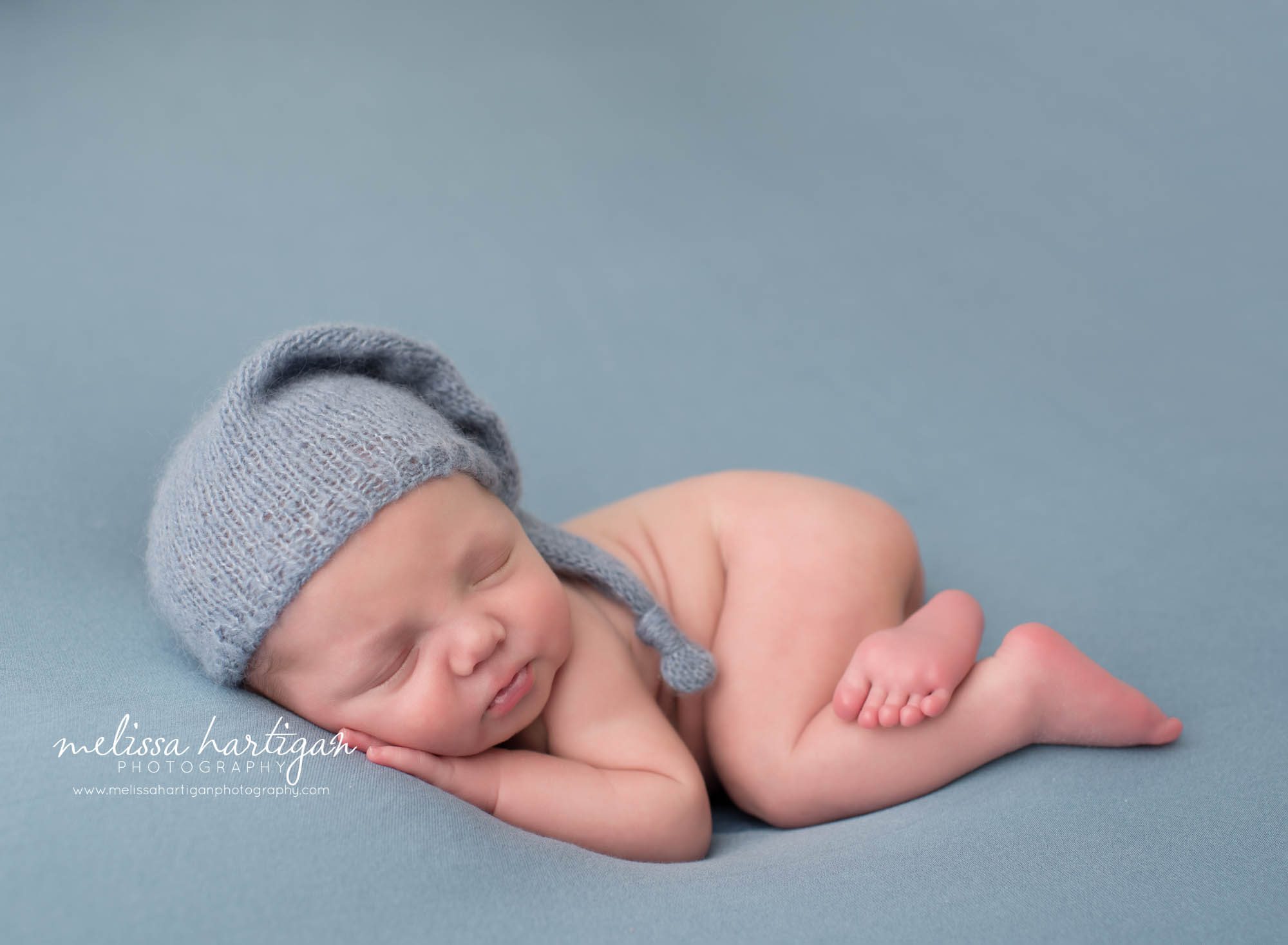 newborn baby boy posed on tummy wearing blue sleepy cap CT newborn photography twins