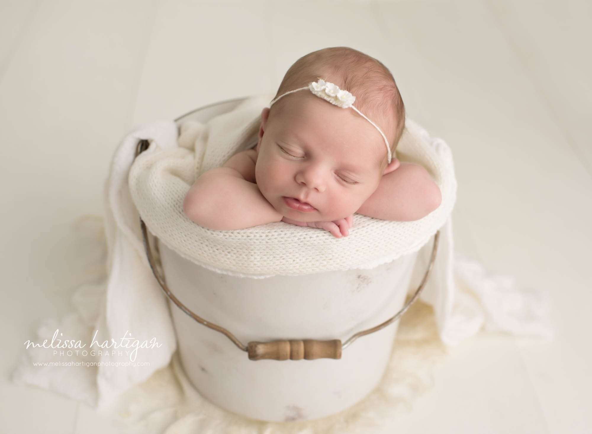 newborn baby girl posed in bucket with cream knit draping layer