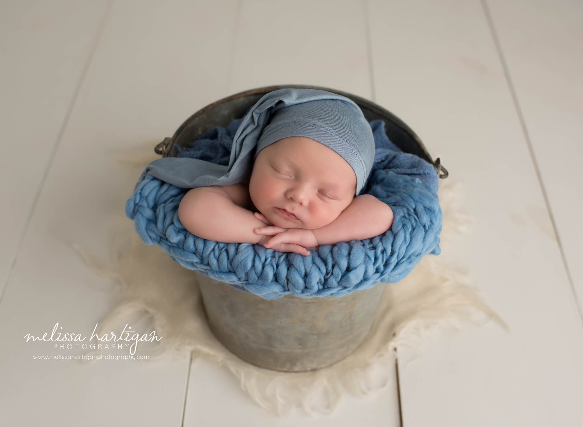 newborn baby boy pose din bucket wearing blue sleepy cap twin newborn photography CT
