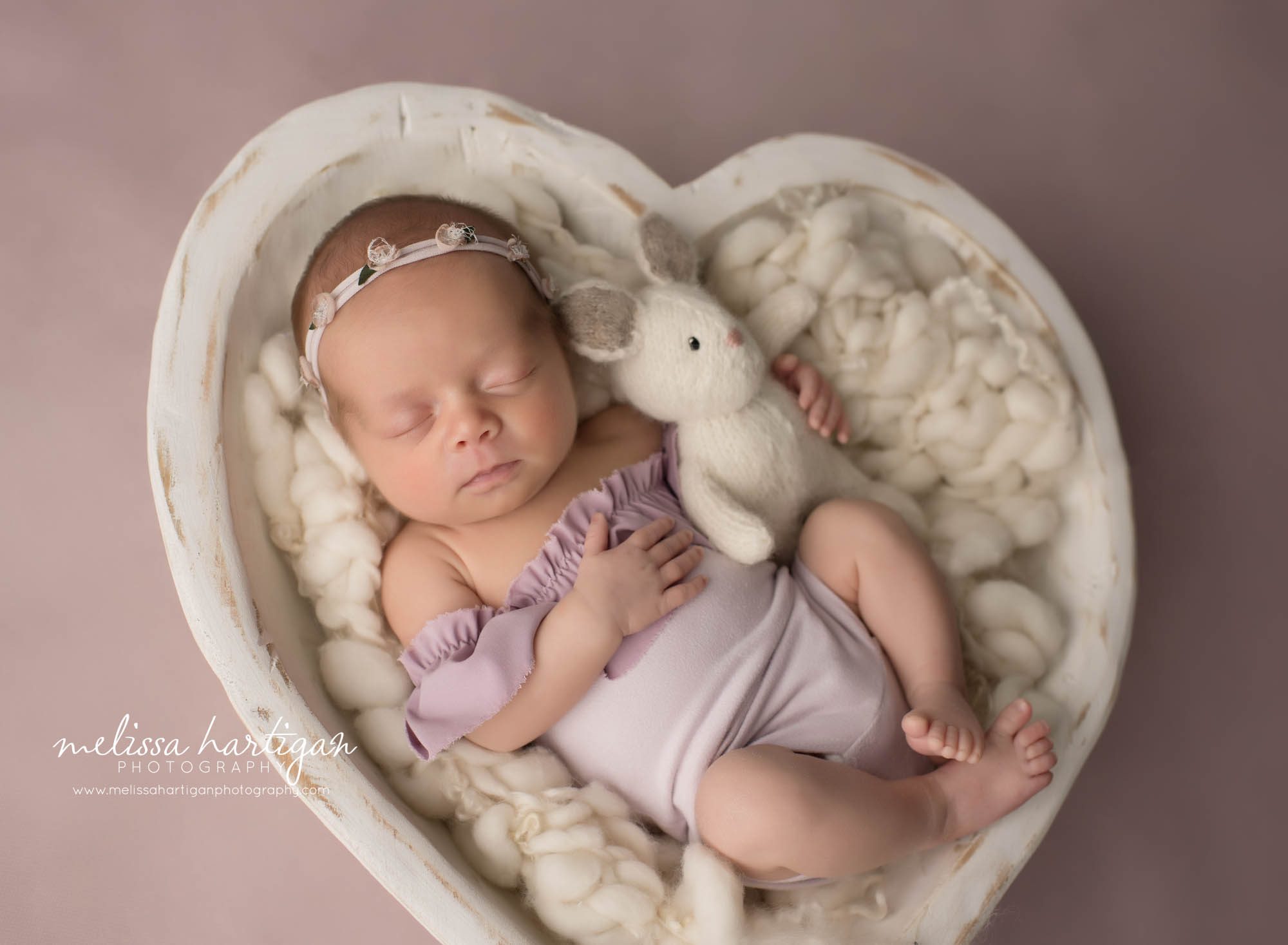 newborn baby girl wearing purple posed in wooden cream heart bowl prop