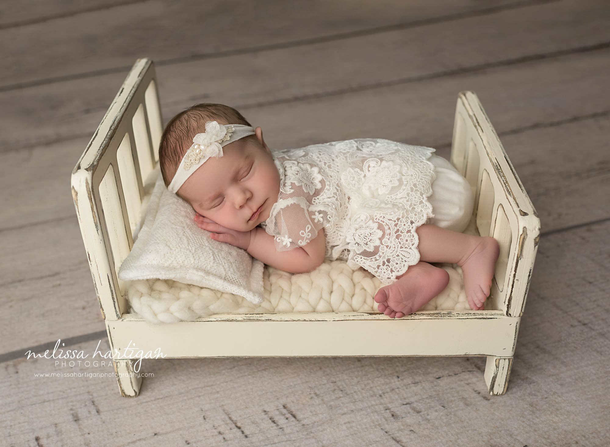 newborn abby girl posed on tummy wearing lace newborn outfit on wooden cream prop bed newborn photography CT