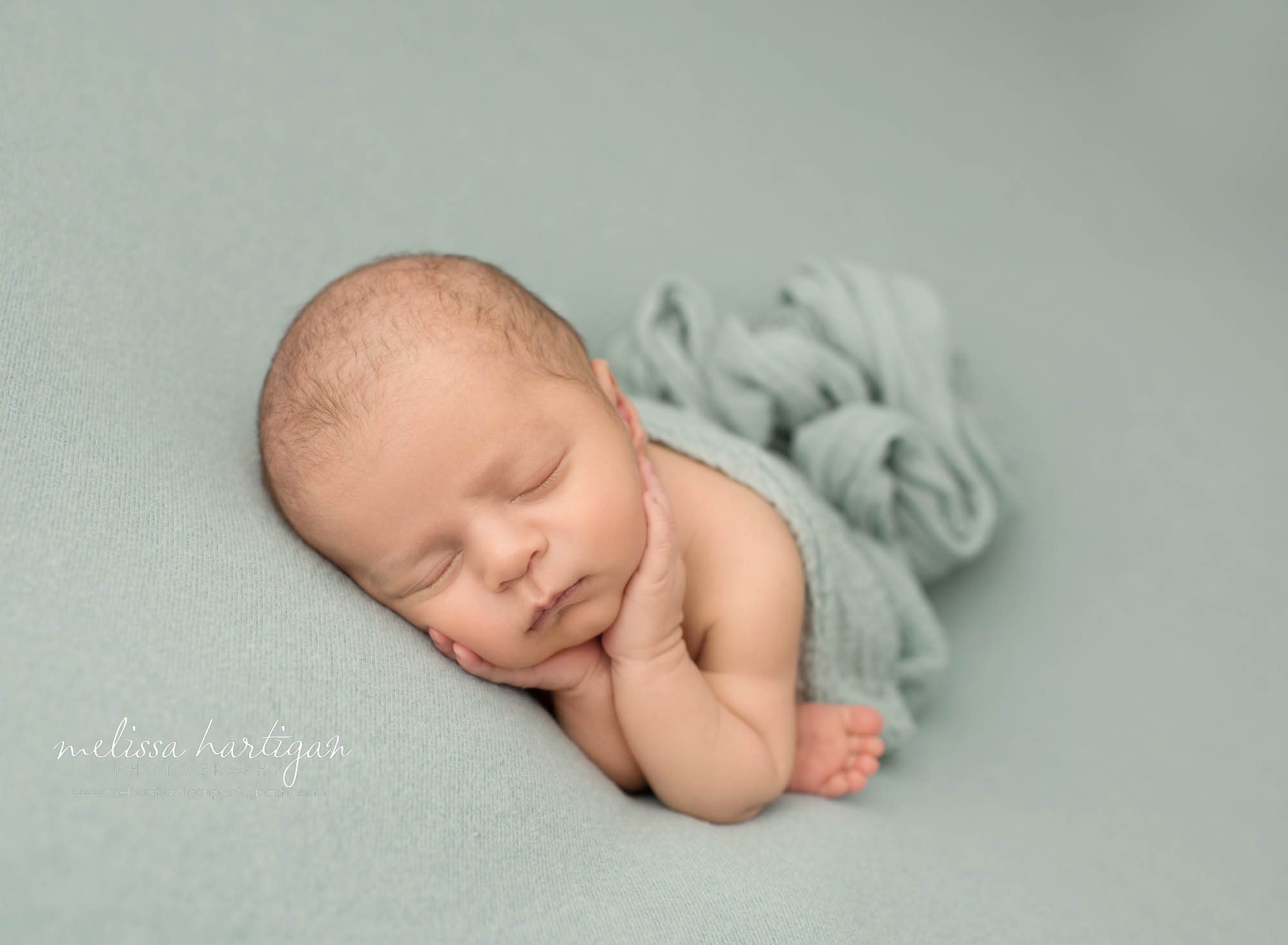 Newborn baby boy posed on sage green backdrop with hands under chin timber pose newborn photogrpahy