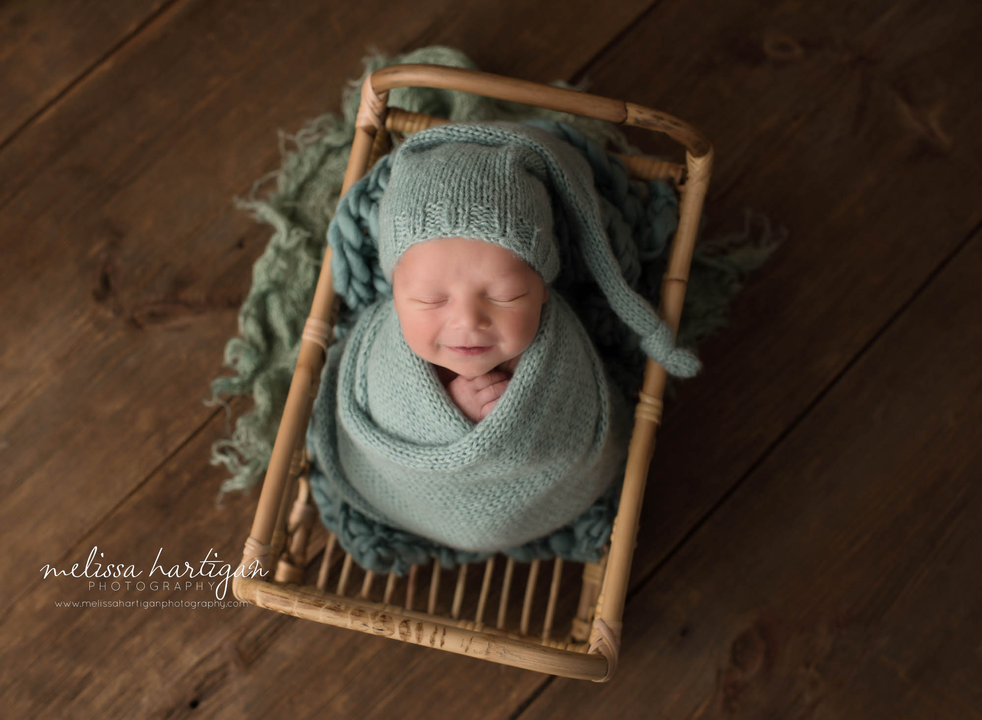 newborn abby boy posed in basket wearing knitted sleepy cap smiling happy baby