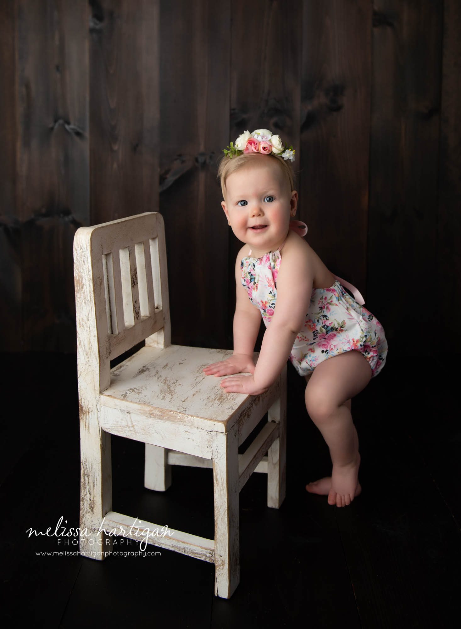 baby girl standing up at cream wooden chair prop in milestone photoshoot windsor CT baby photography