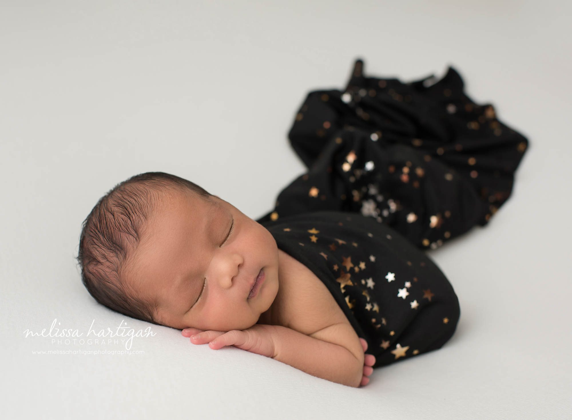 newborn baby boy posed on tummy with black wrap draped over him