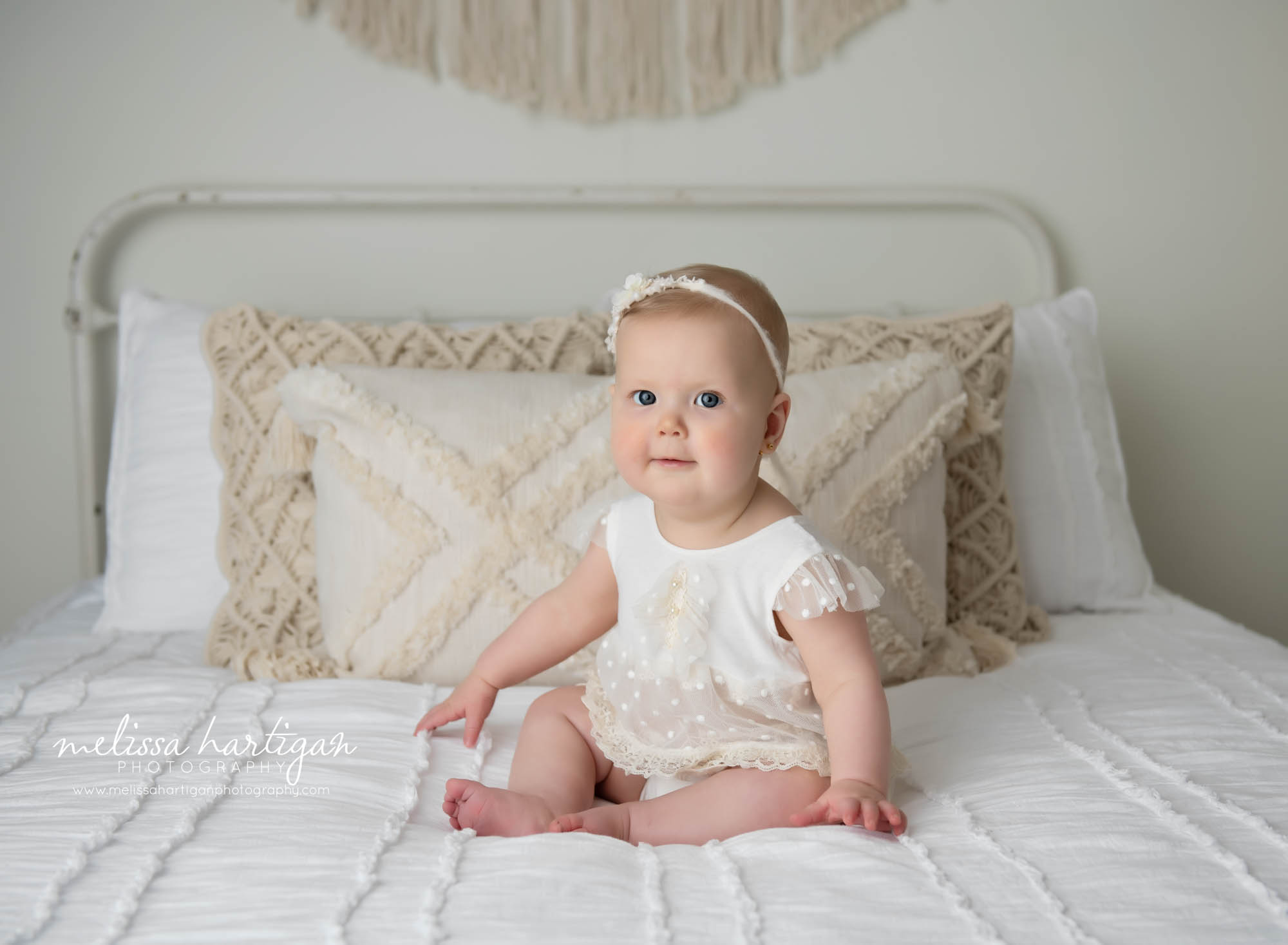 baby girl sitting on bed in photography studio windsor baby photographer