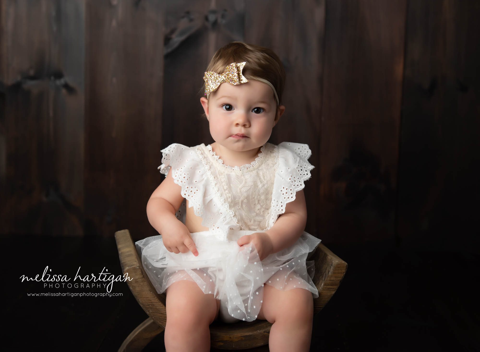 baby girl sitting on curved wooden bench