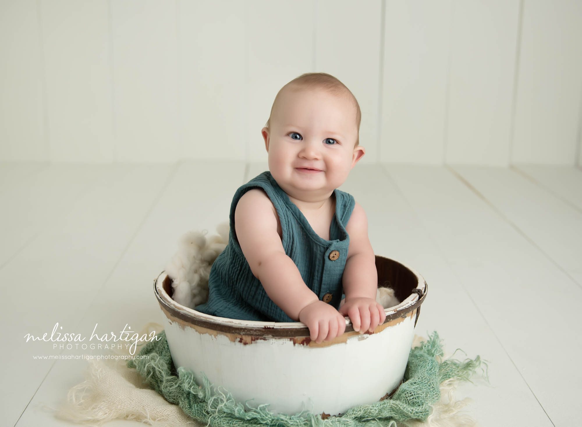 Baby boy sitting in bowl prop in baby milestone photography studio wearing green baby outfit ellingtony ct baby photography