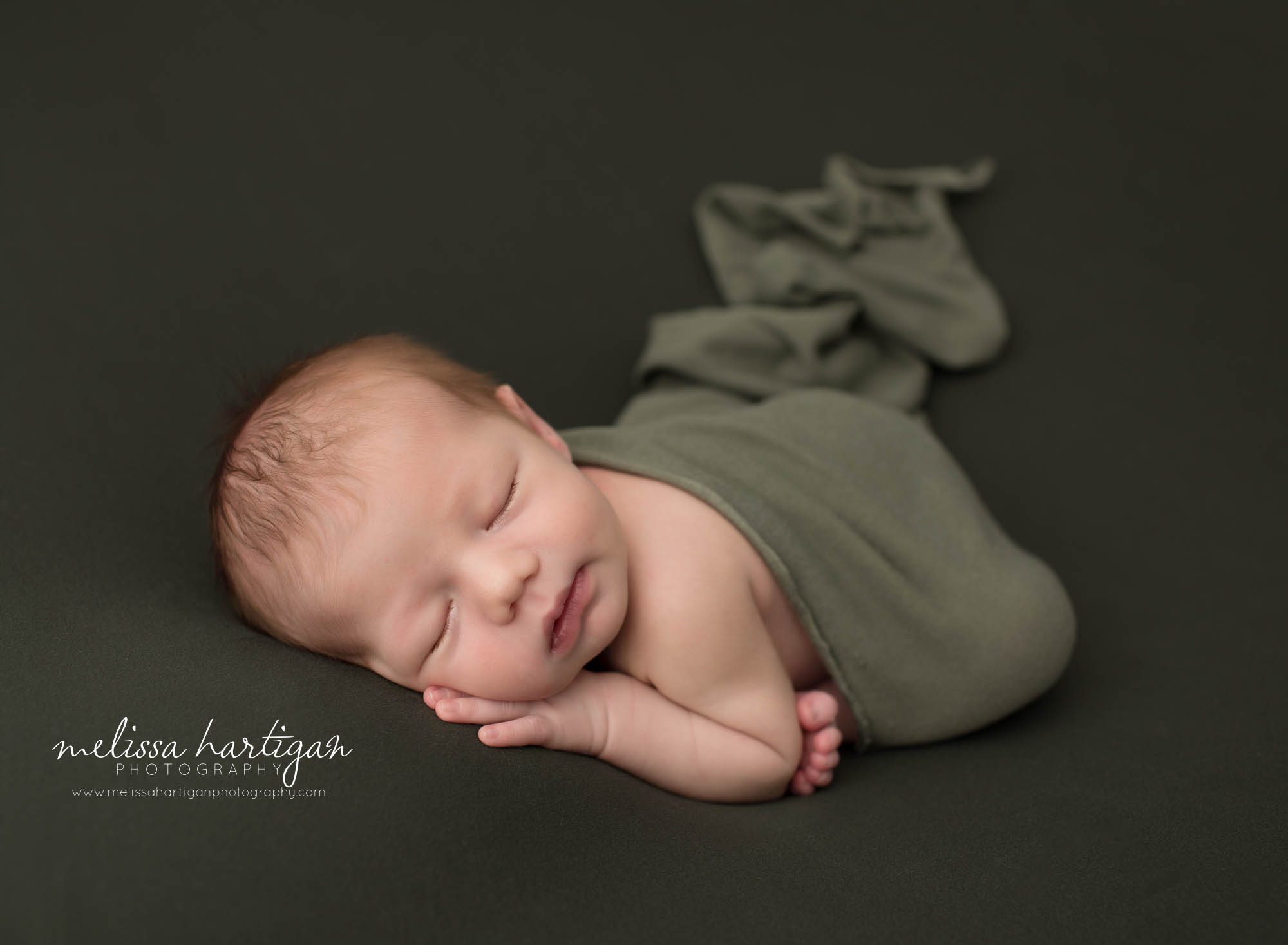 newborn baby boy posed on tummy draped with green wrap