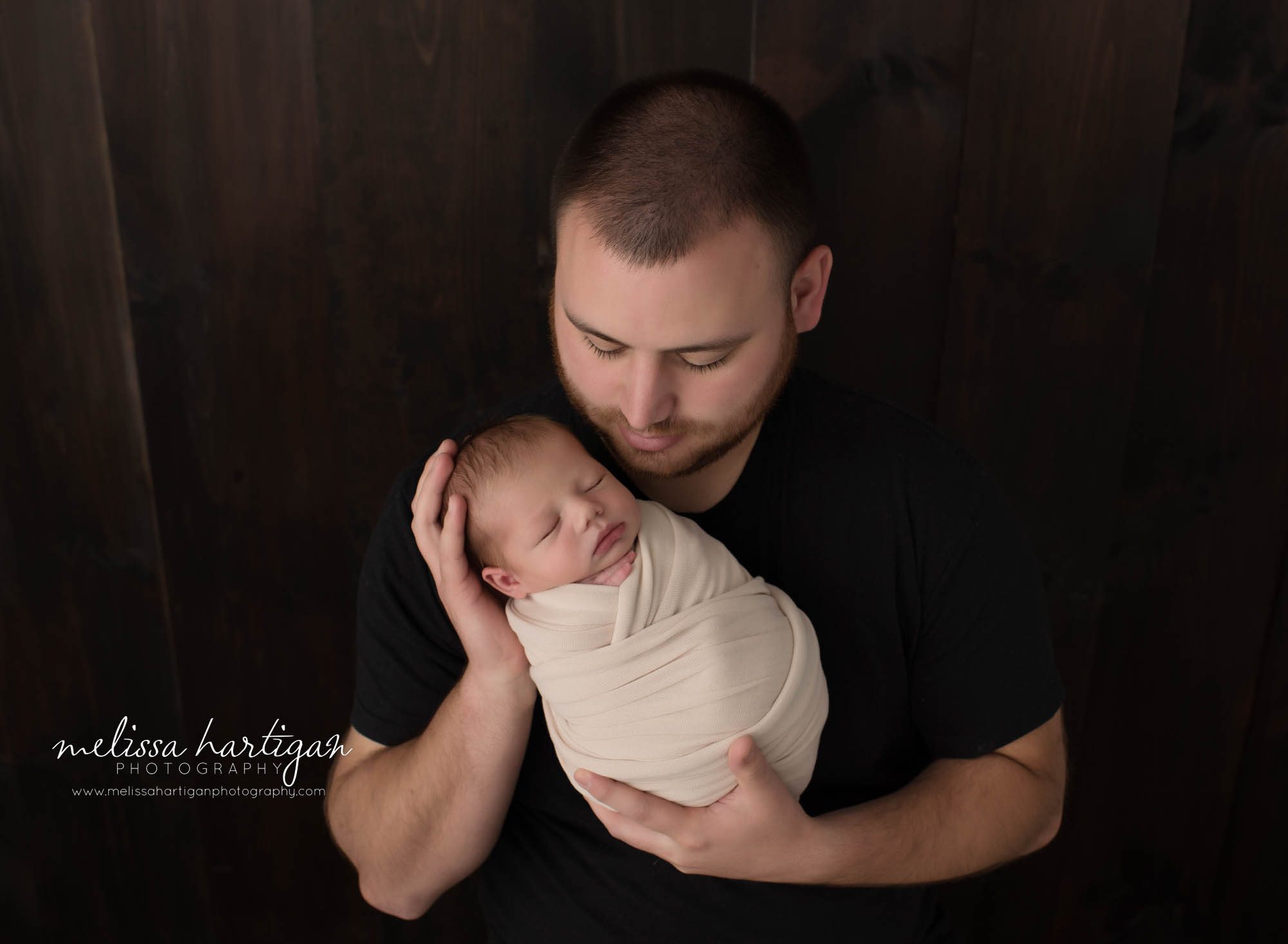 dad holding and looking down at newborn son parents pose