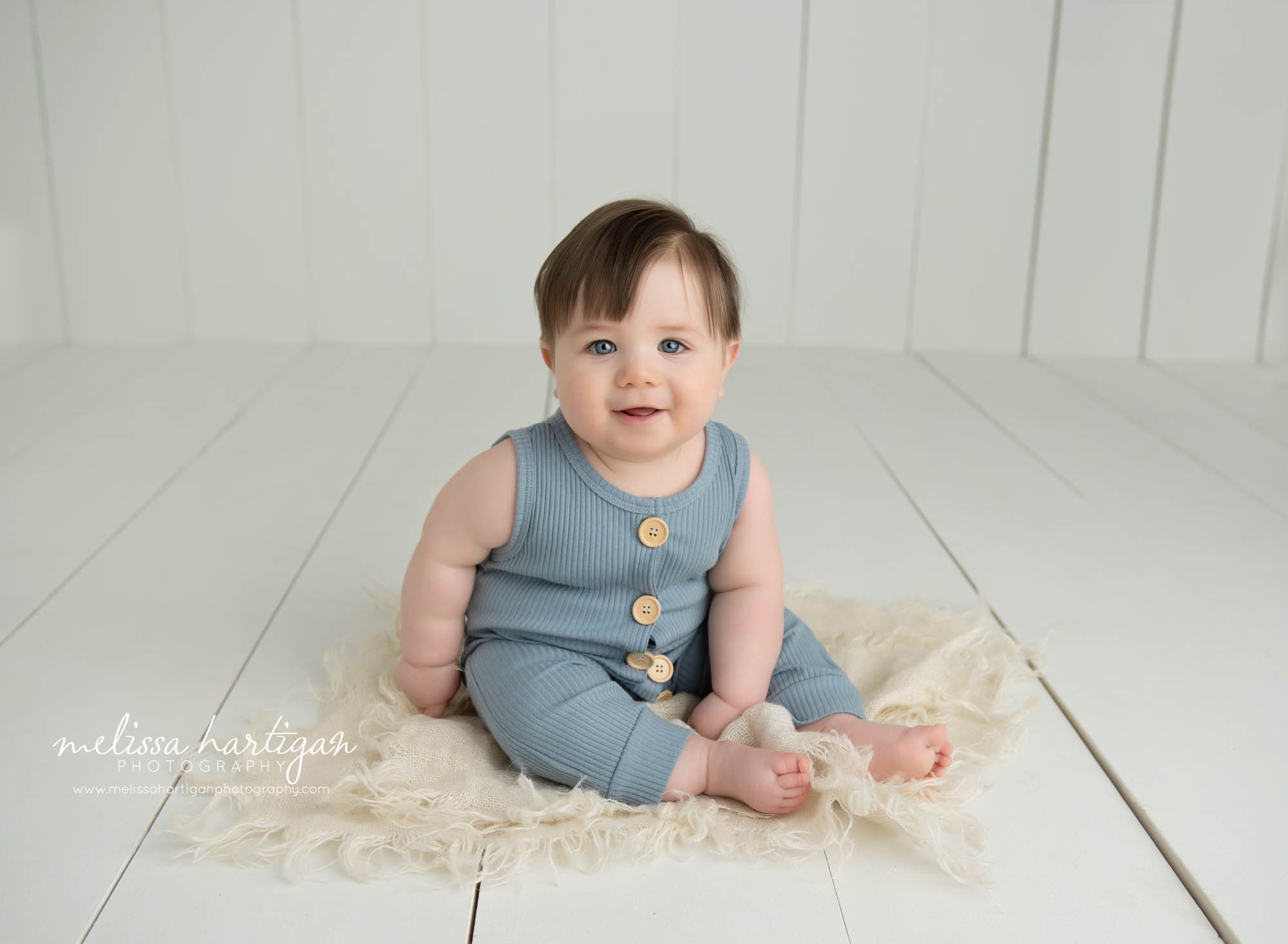 Baby boy sitting on wooden boards in photography studio wearing blue baby outfit happy smiling Glastonbury CT baby Photography