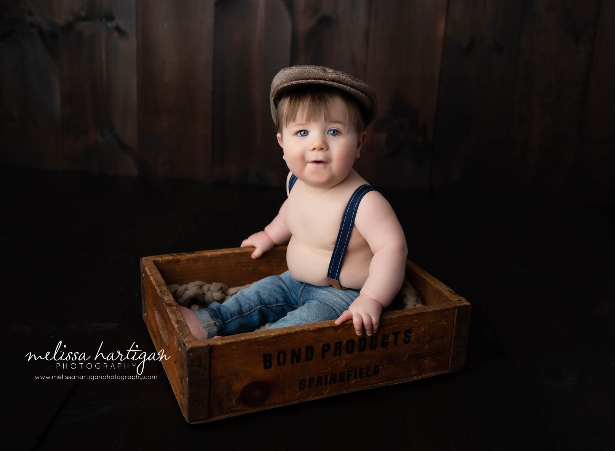 Baby boy sitting in wooden crate in studio photoshoot