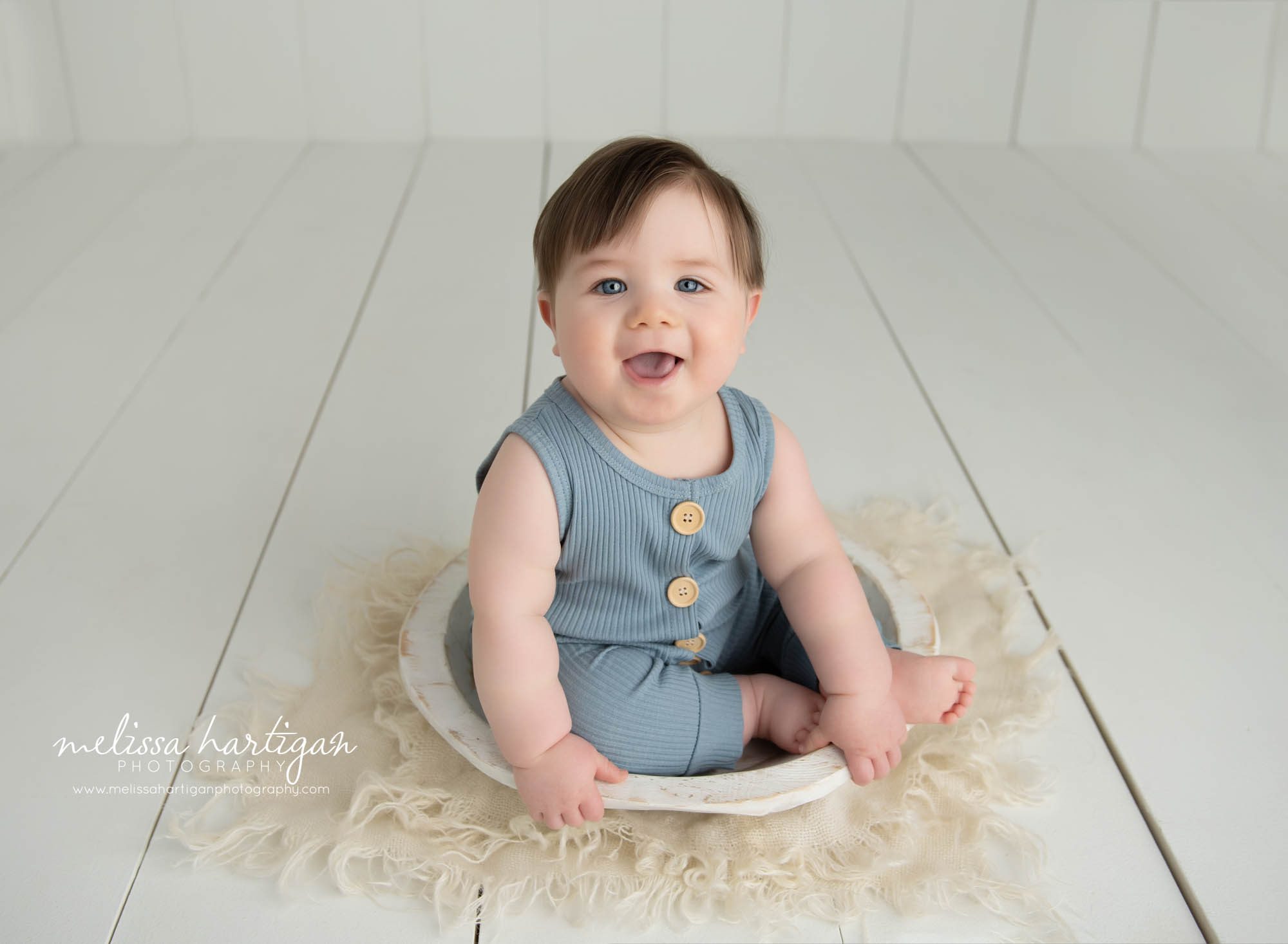 happy smiling baby boy sitting in cream wooden bowl wearing blue button down sitter outfit Glastonbury CT baby Photography