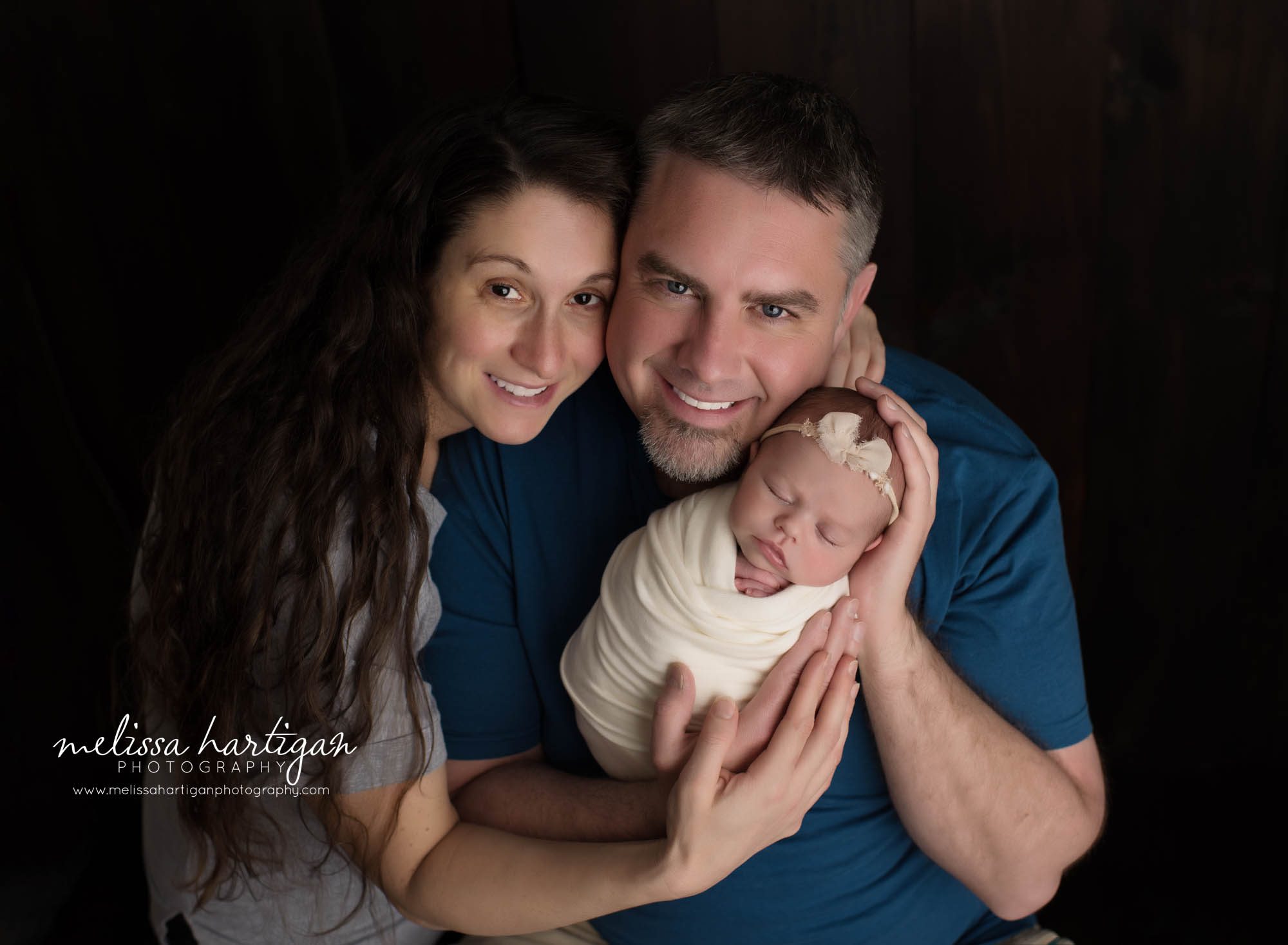 mom dad and baby daughter swaddled in cream wrap posed together for family pose