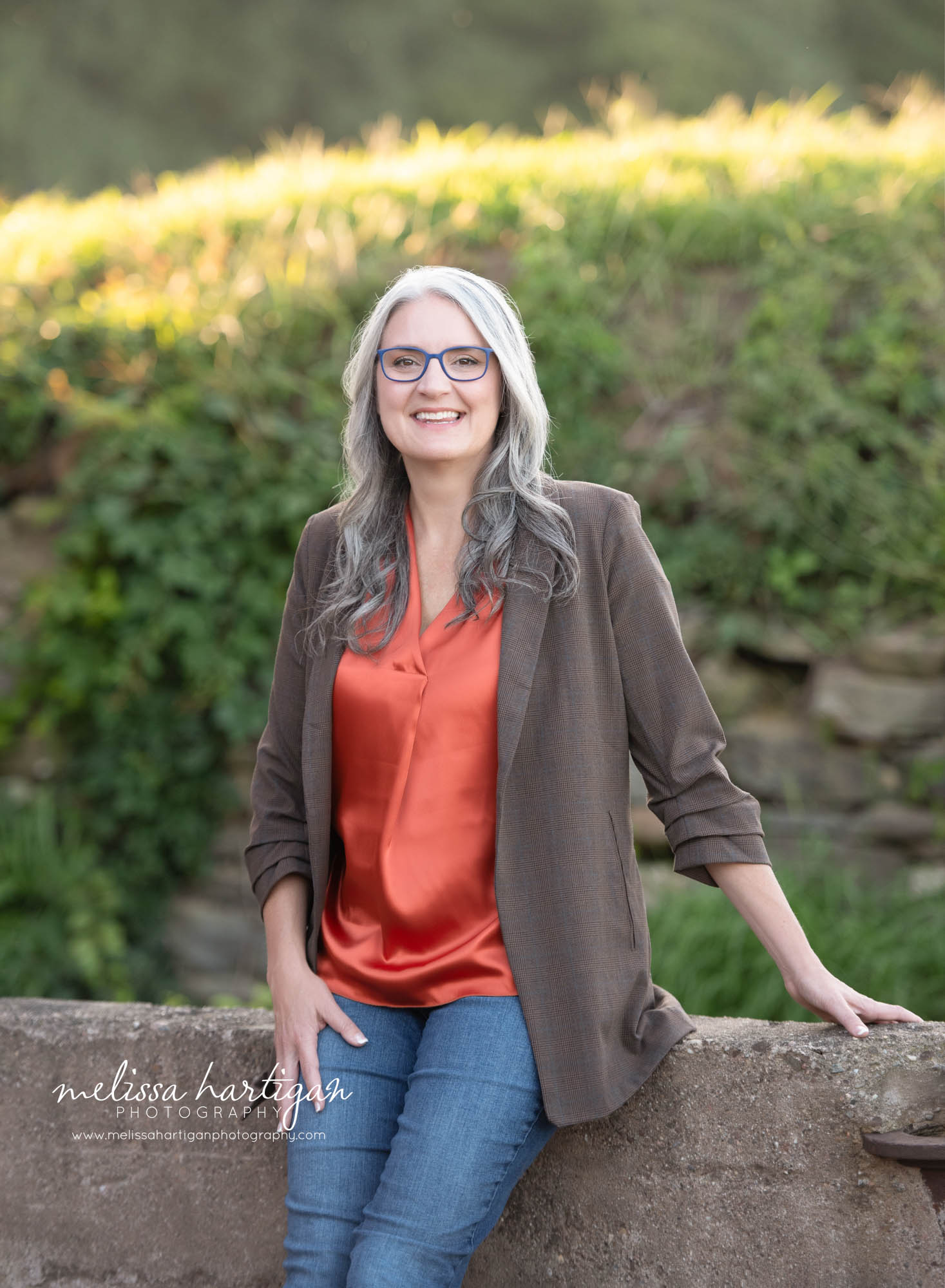 woman leaning sitting against stone wall happy smiling professional photography