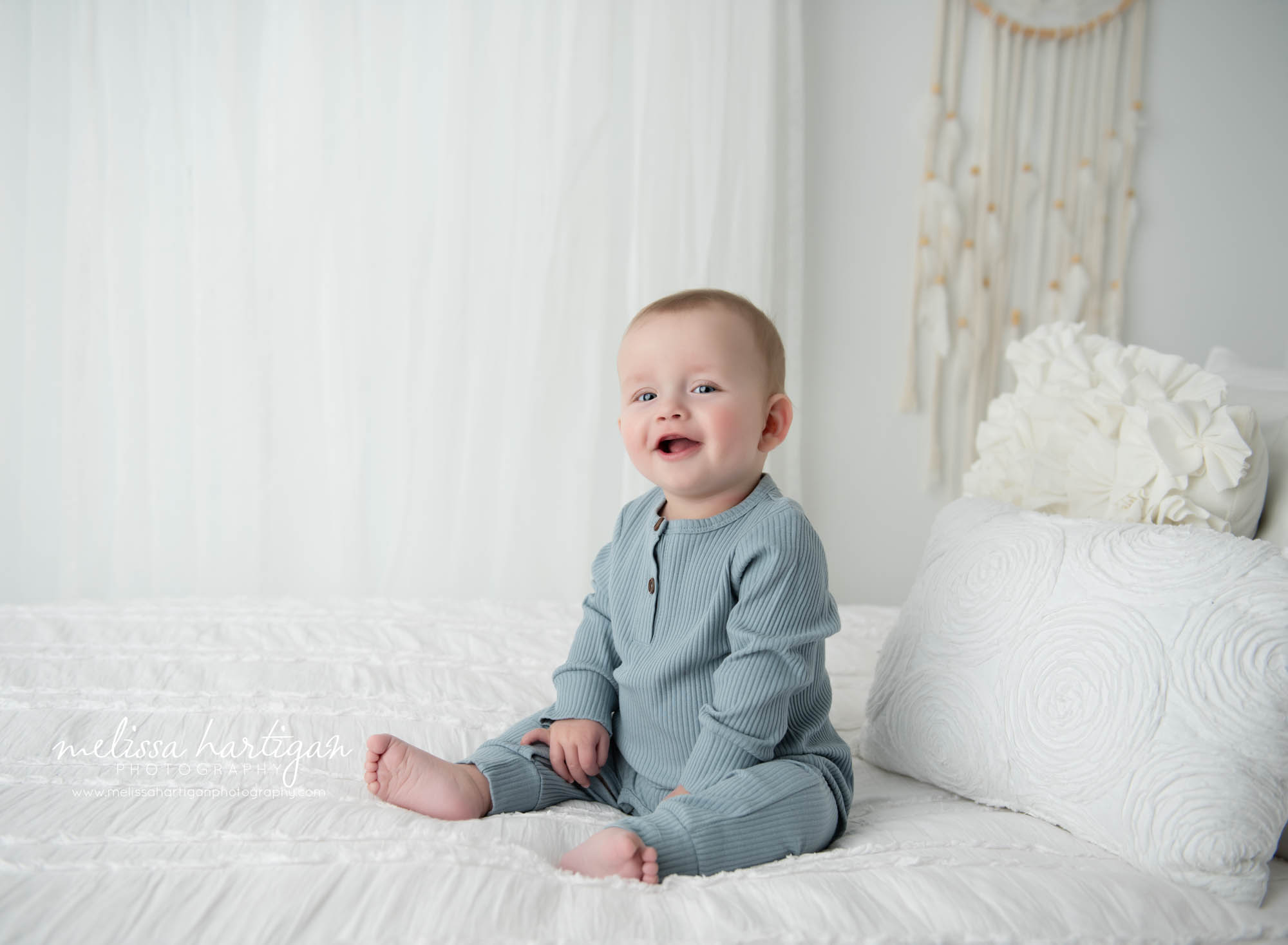 baby boy sitting on bed in studio happy smiling Tolland CT baby photographer