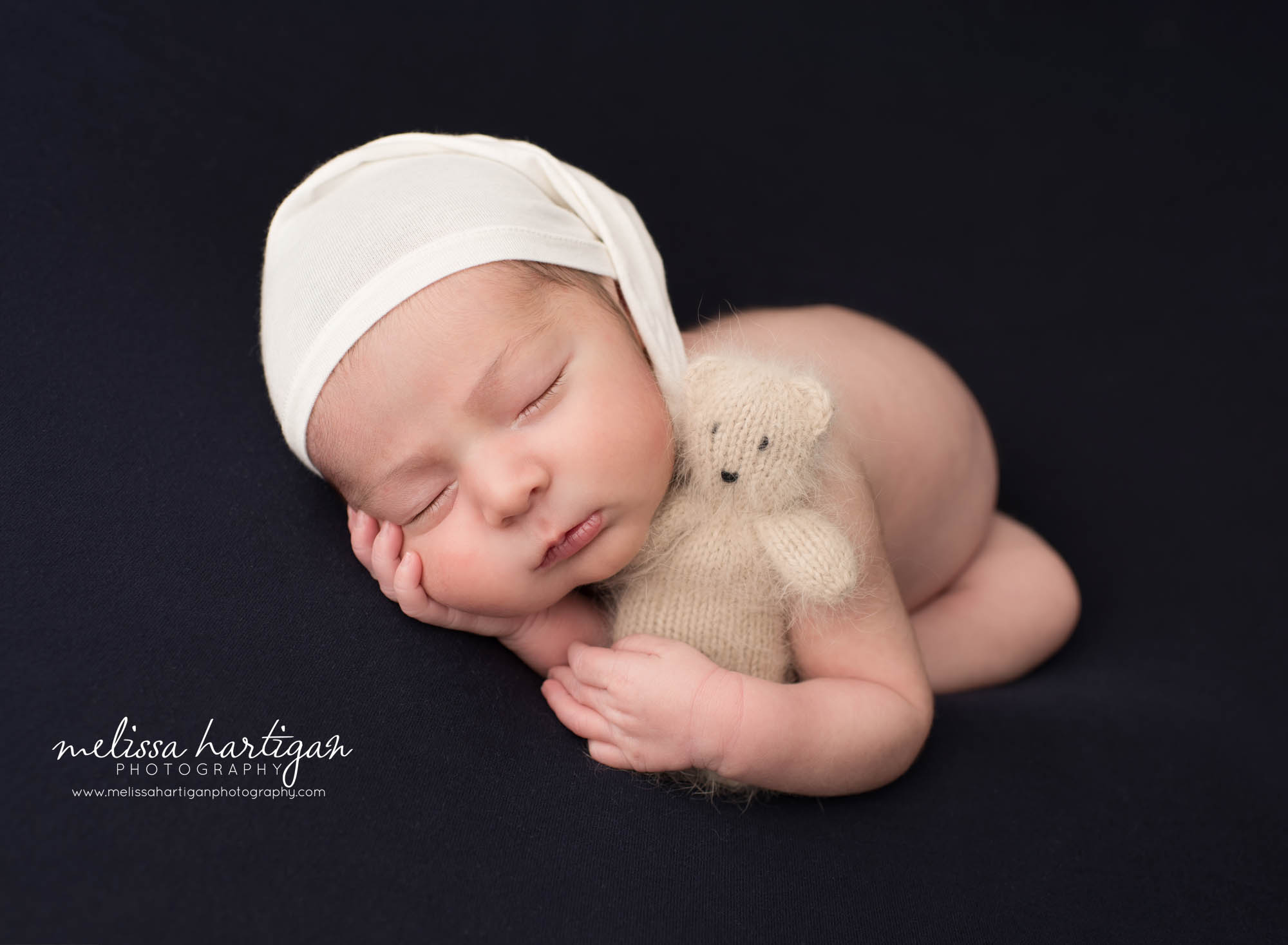 newborn baby boy posed holding teddy bear