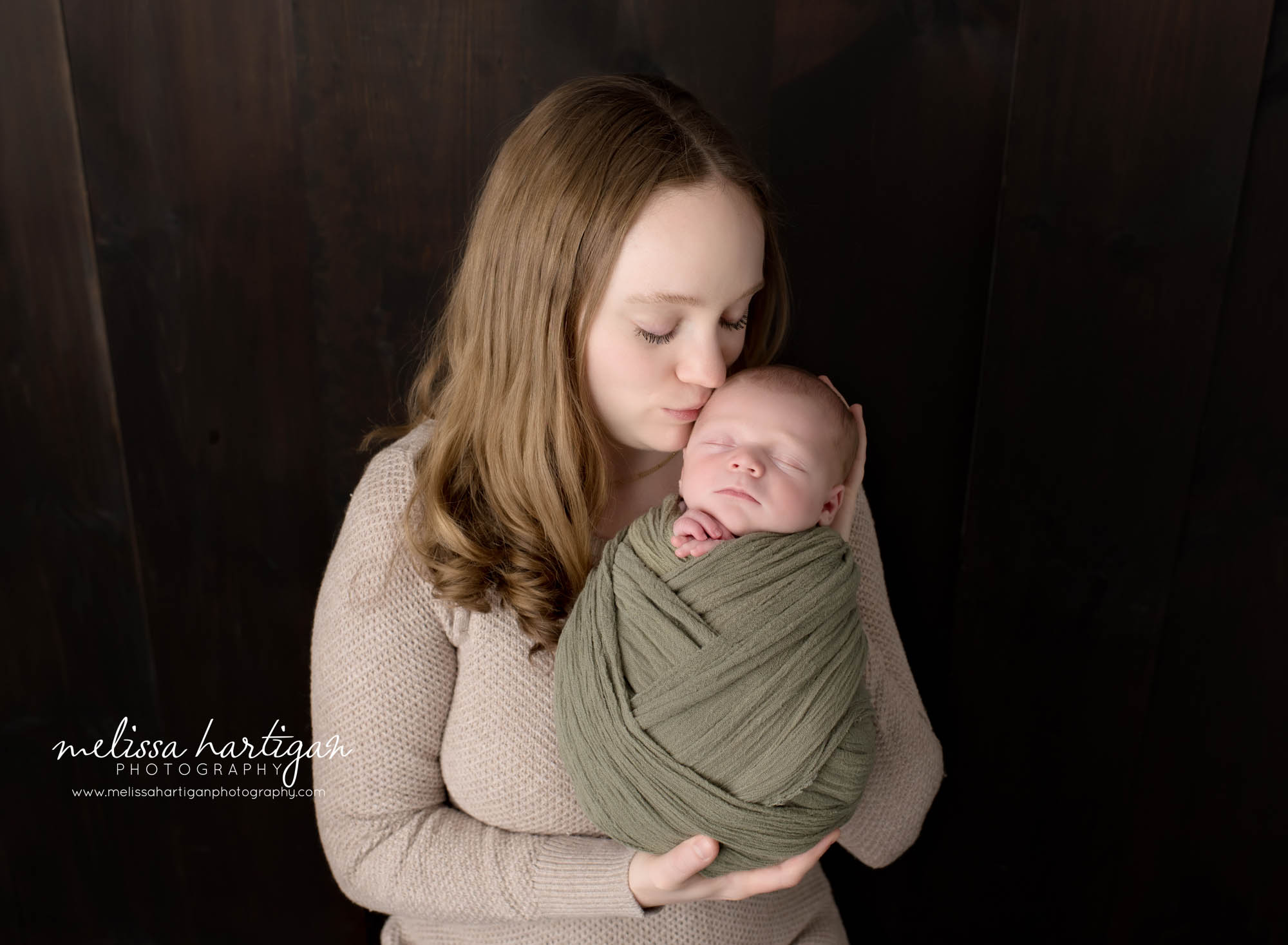 mom kissing newborn son on forehead