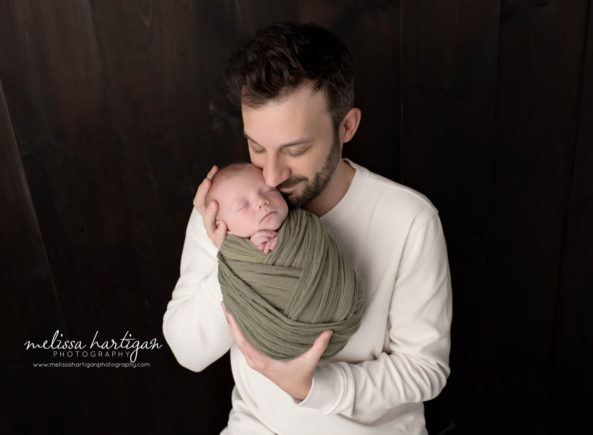 dad holding newborn son parents pose