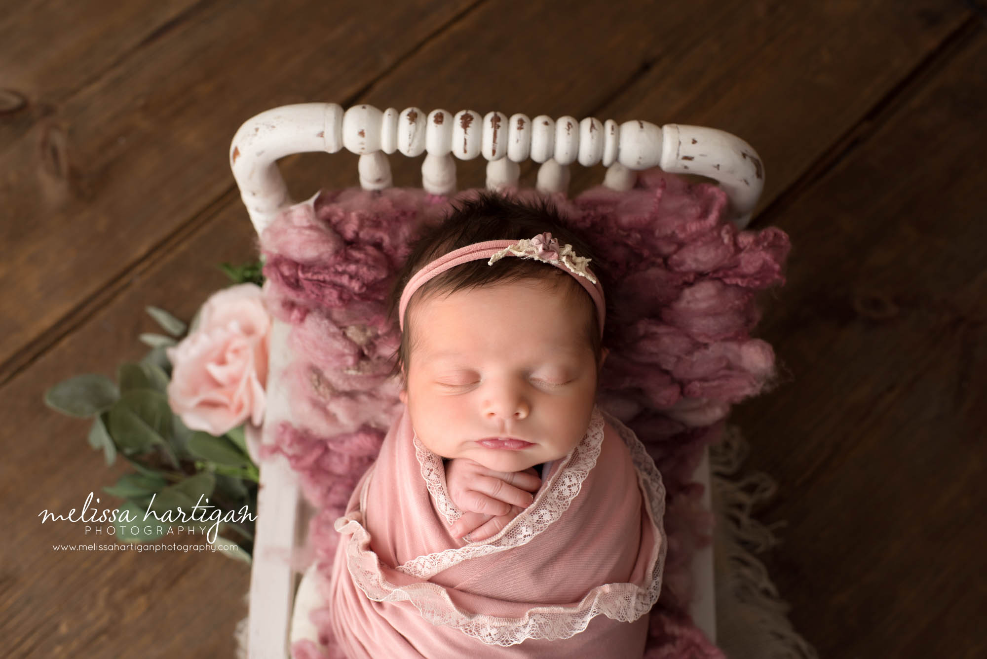 newborn baby girl wrapped in pink wrap posed on bed with flowers Niantic CT Newborn photography