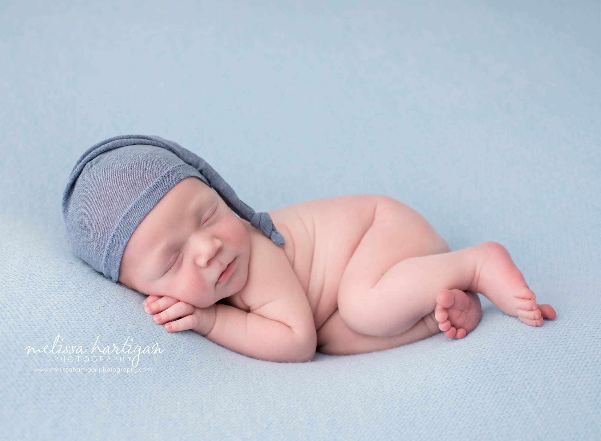 newborn baby boy posed on side wearing blue sleepy cap newborn photography hebron