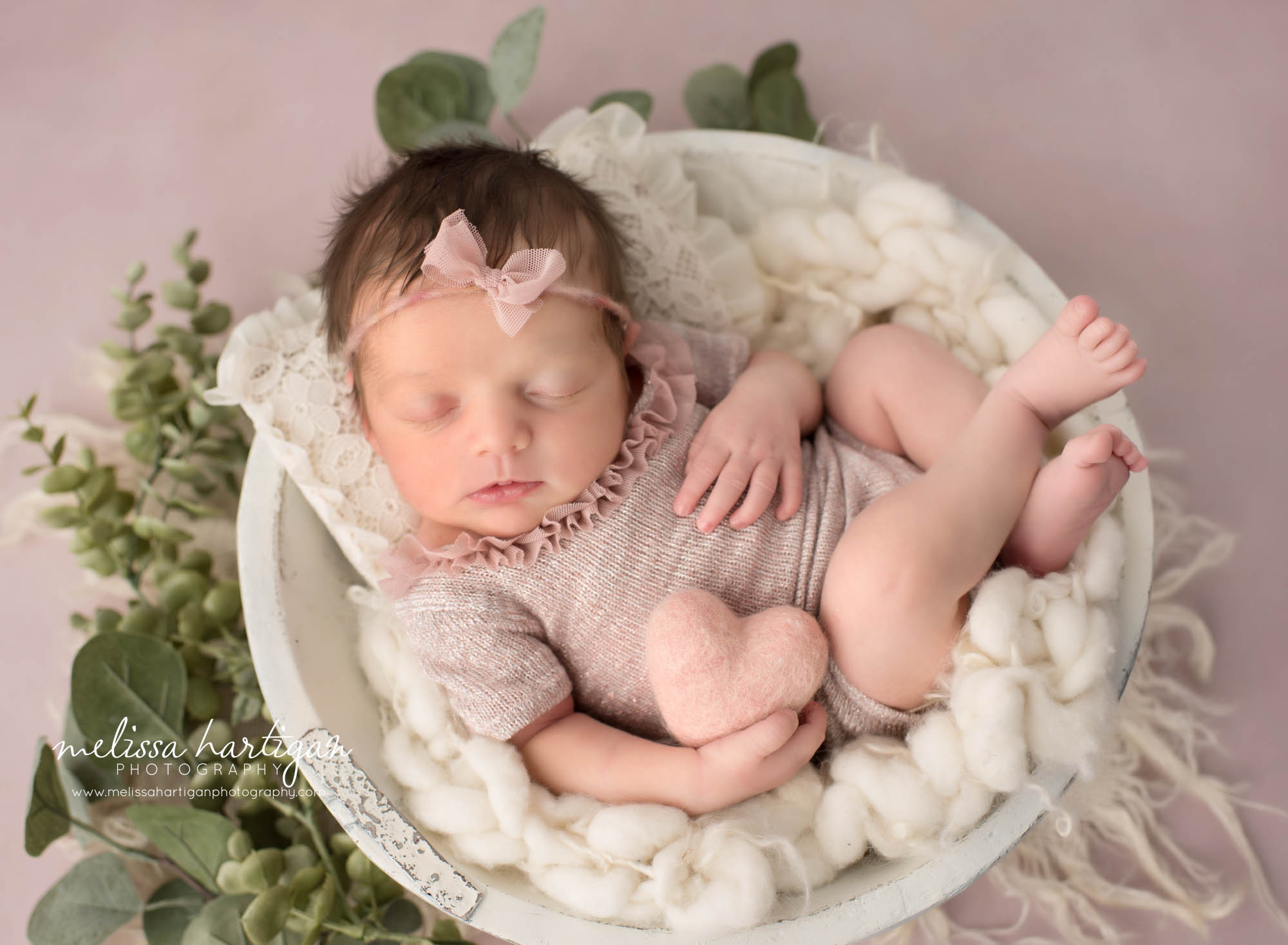 newborn baby girl posed on cream wooden bowl wearing pink newborn outfit and wearing pink bow headband Niantic CT Newborn photography