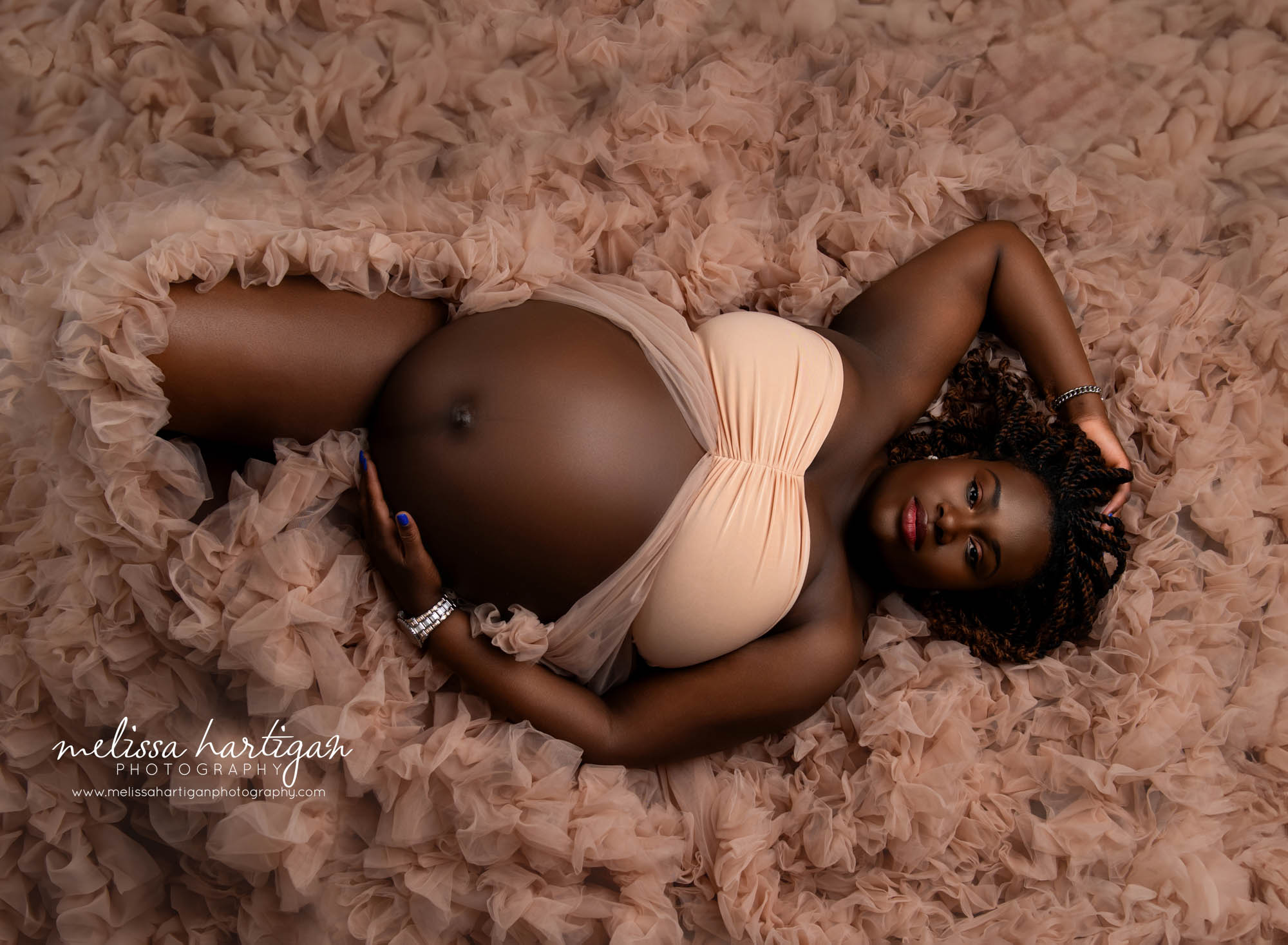 mom laying down holding baby bump with maternity tulle surrounding her Maternity Photography Hartford County