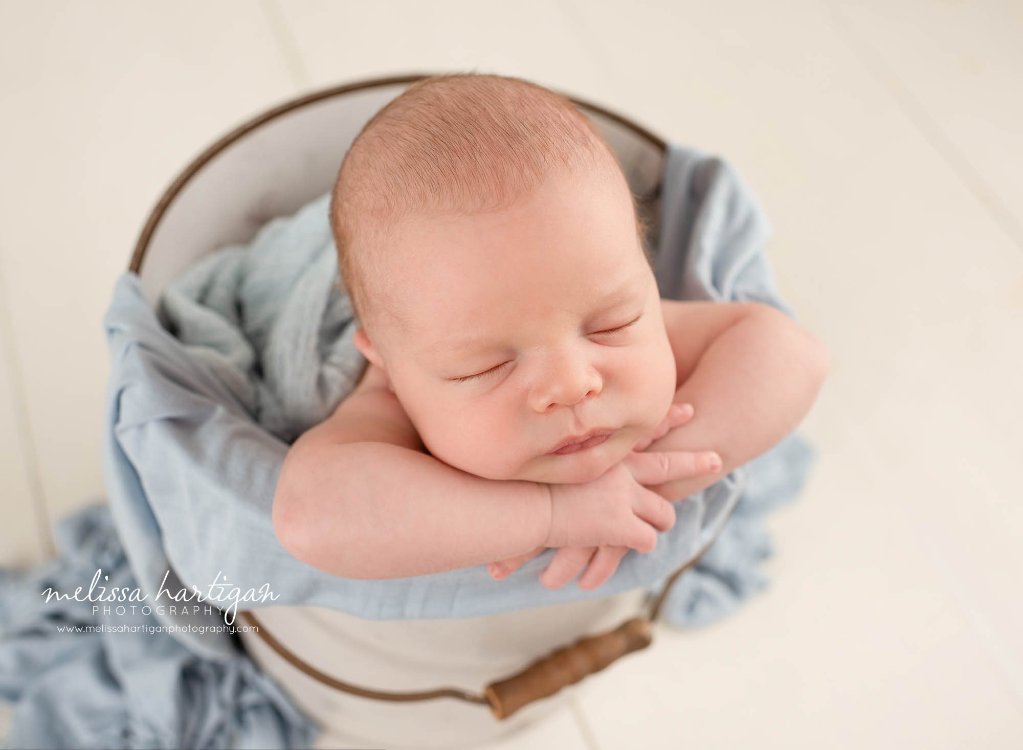 newborn baby boy posed in bucket with blue layers