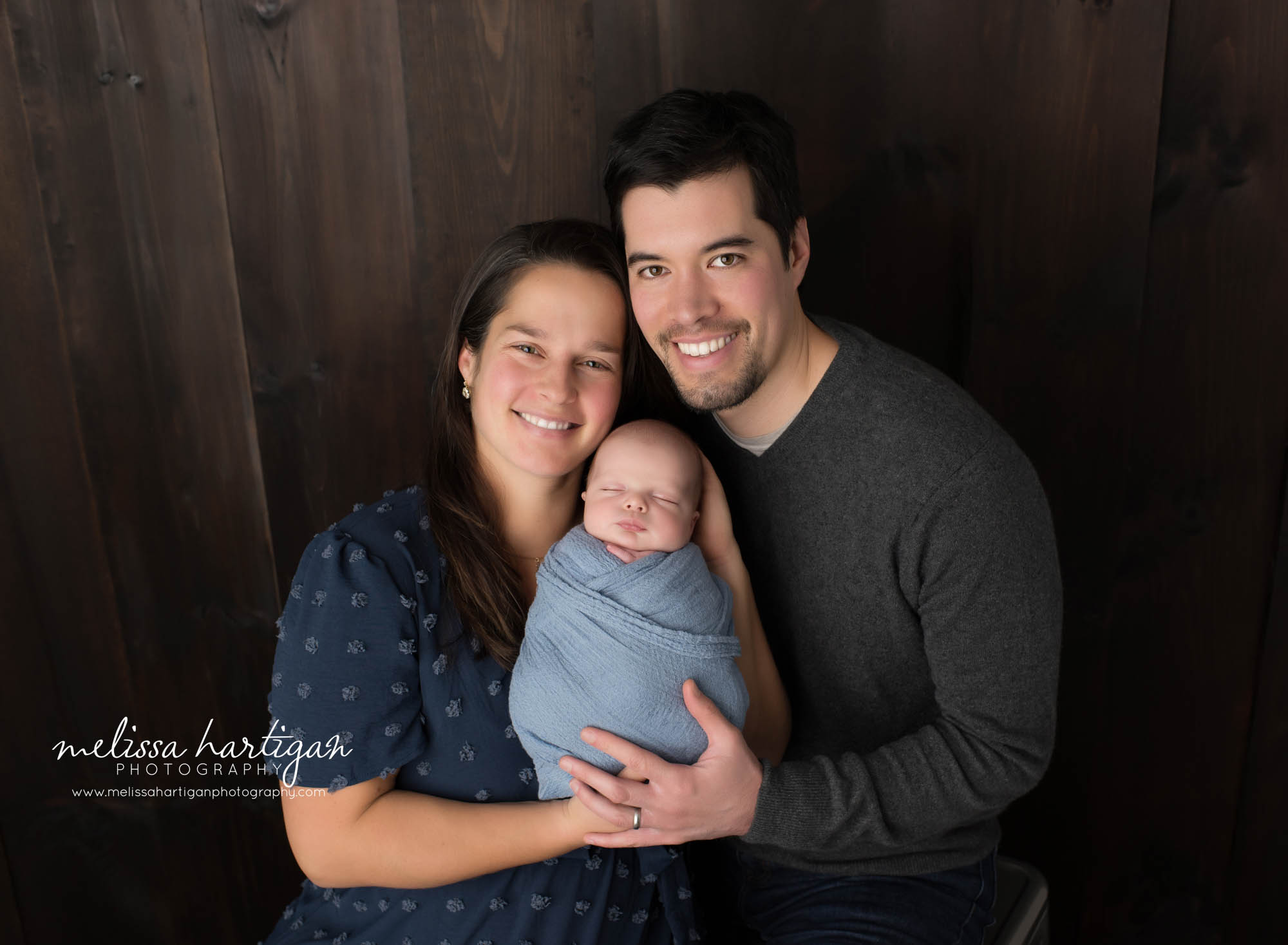 mom dad holding newborn son in parents pose