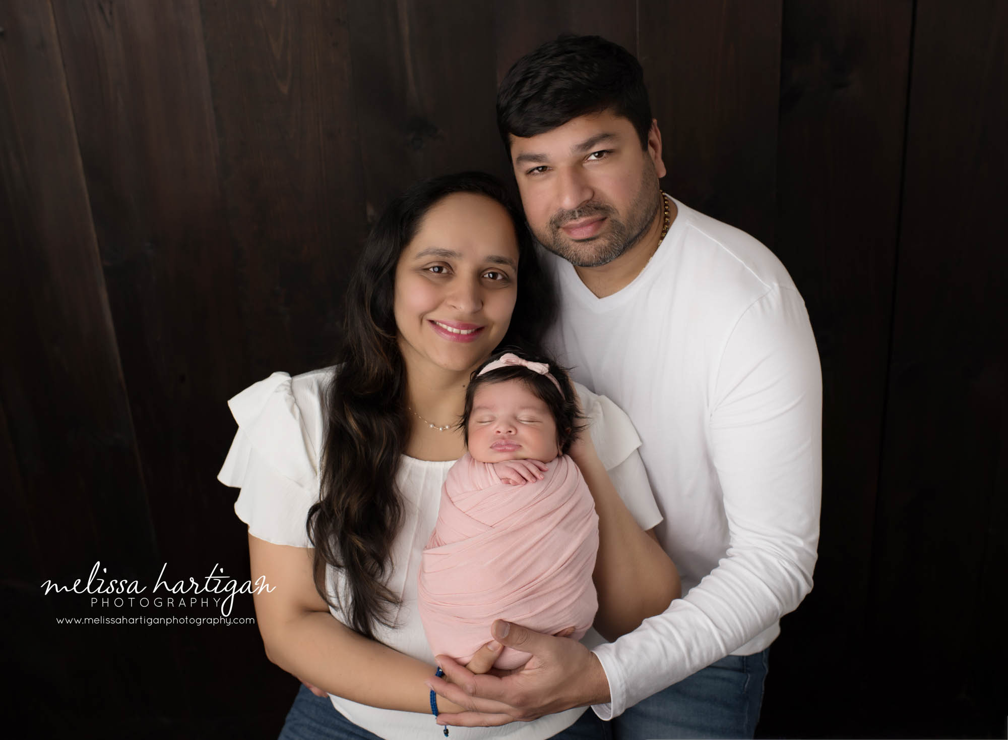 mom dad and baby daughter posed in parents pose in newborn photoshoot