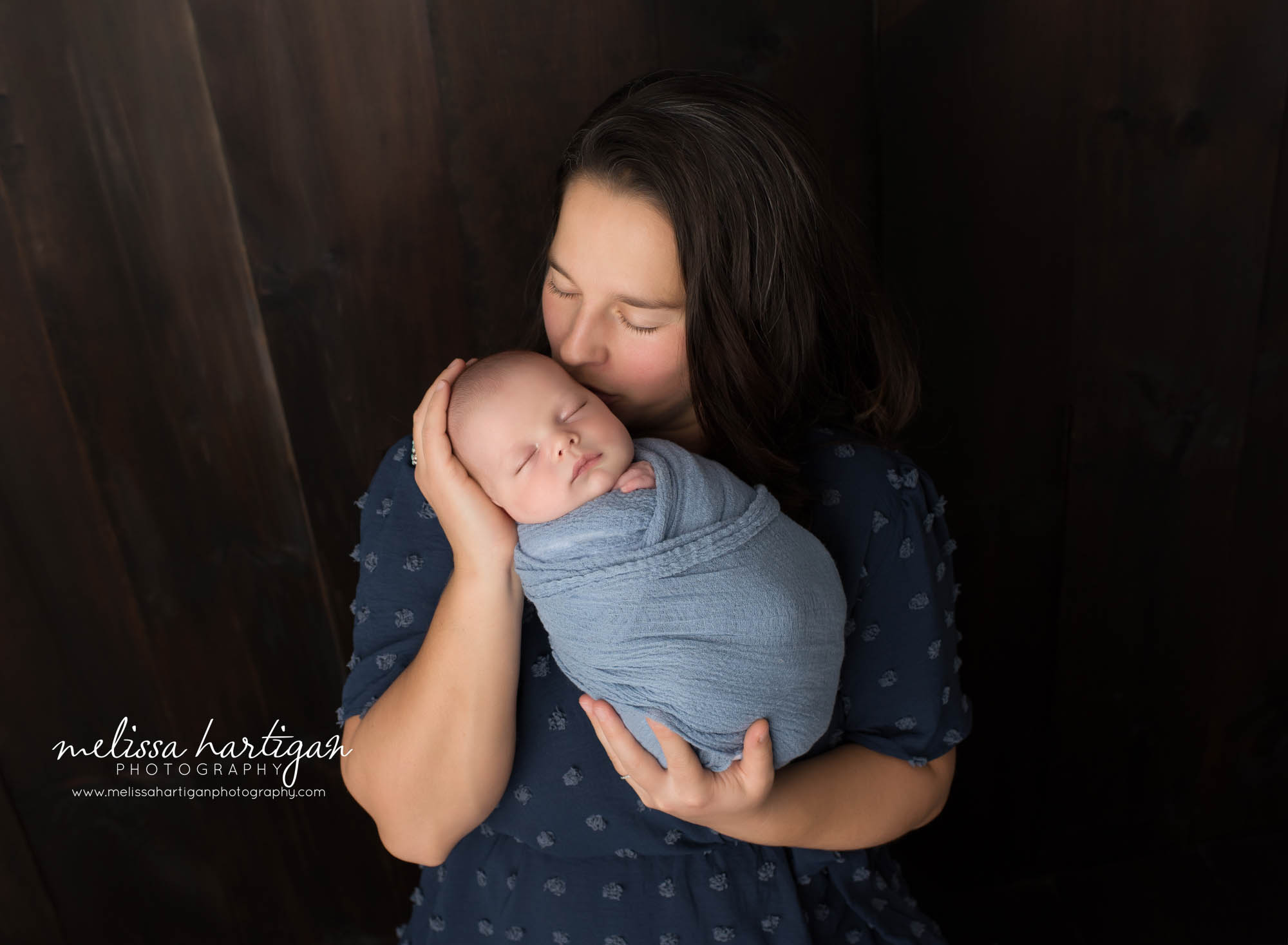 mom kissing newborn son on cheek in parents pose