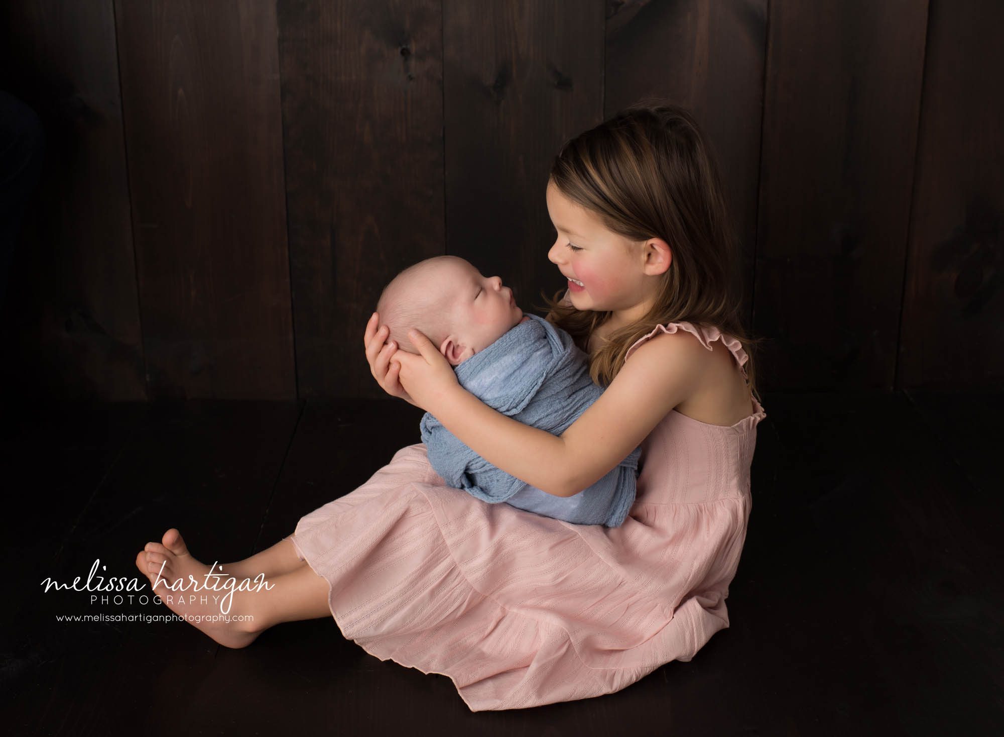 big sister holding newborn baby brother