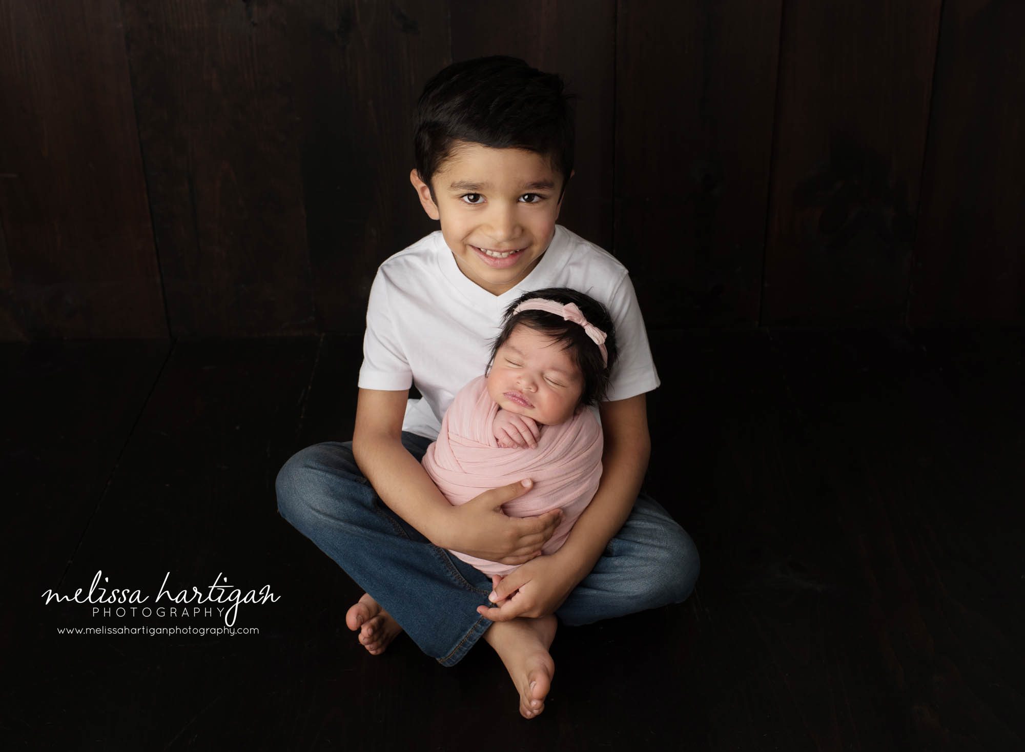 big brother holding newborn baby sister in siblings pose