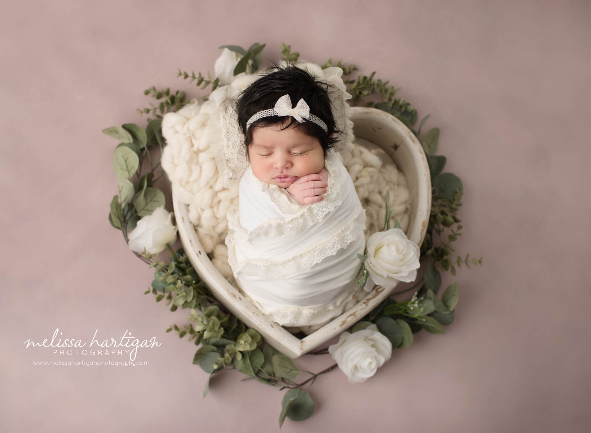 newborn baby girl posed in heart shaped wooden bowl wearing bow headband Suffield CT Newborn photography