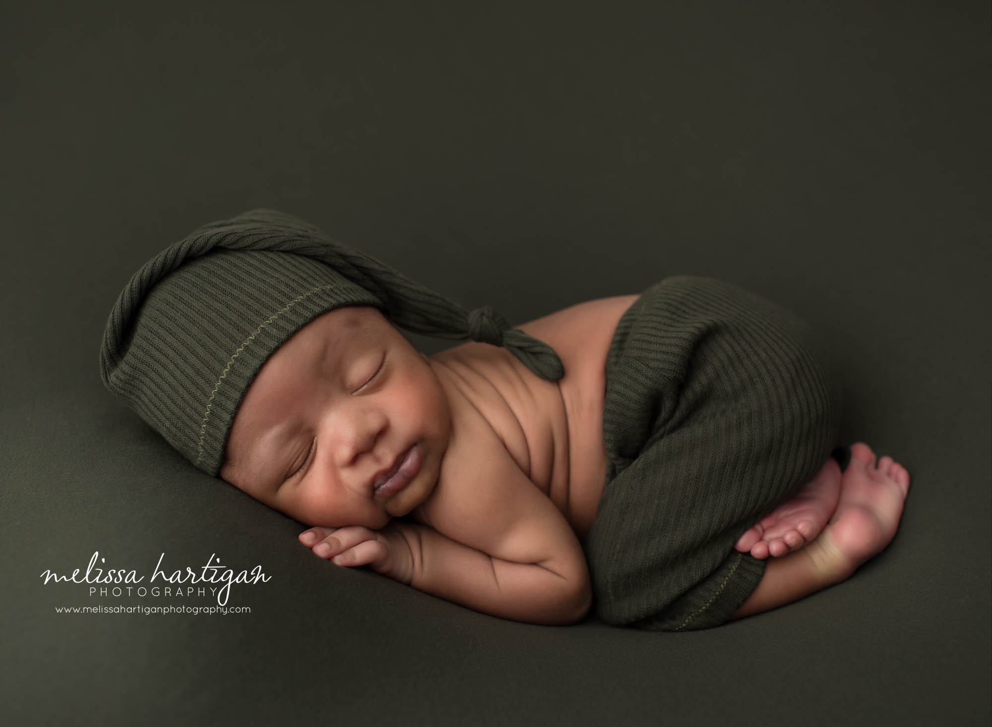 Newborn baby boy posed bum up pose wearing green sleepy cap Tolland Newborn Photography