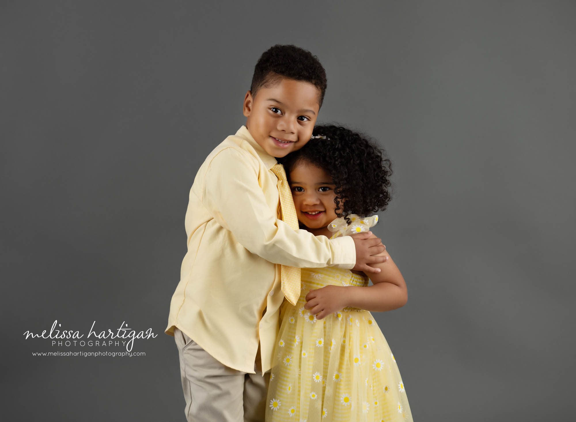 Brother hugging holding little sister in sibling milestone photography session