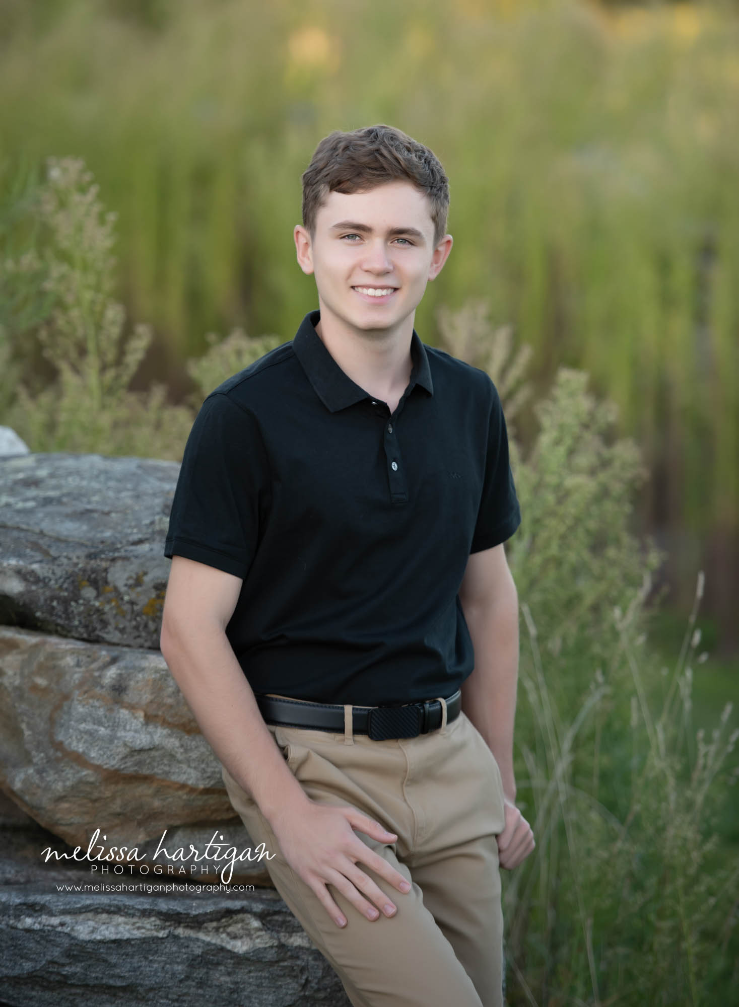 High school senior leaning against rock