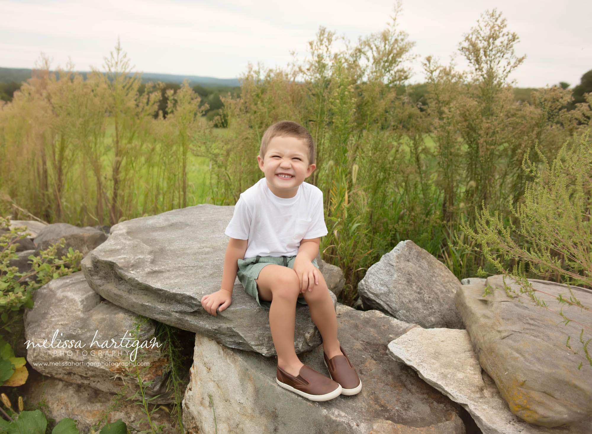 boy sitting on rock happy smiling