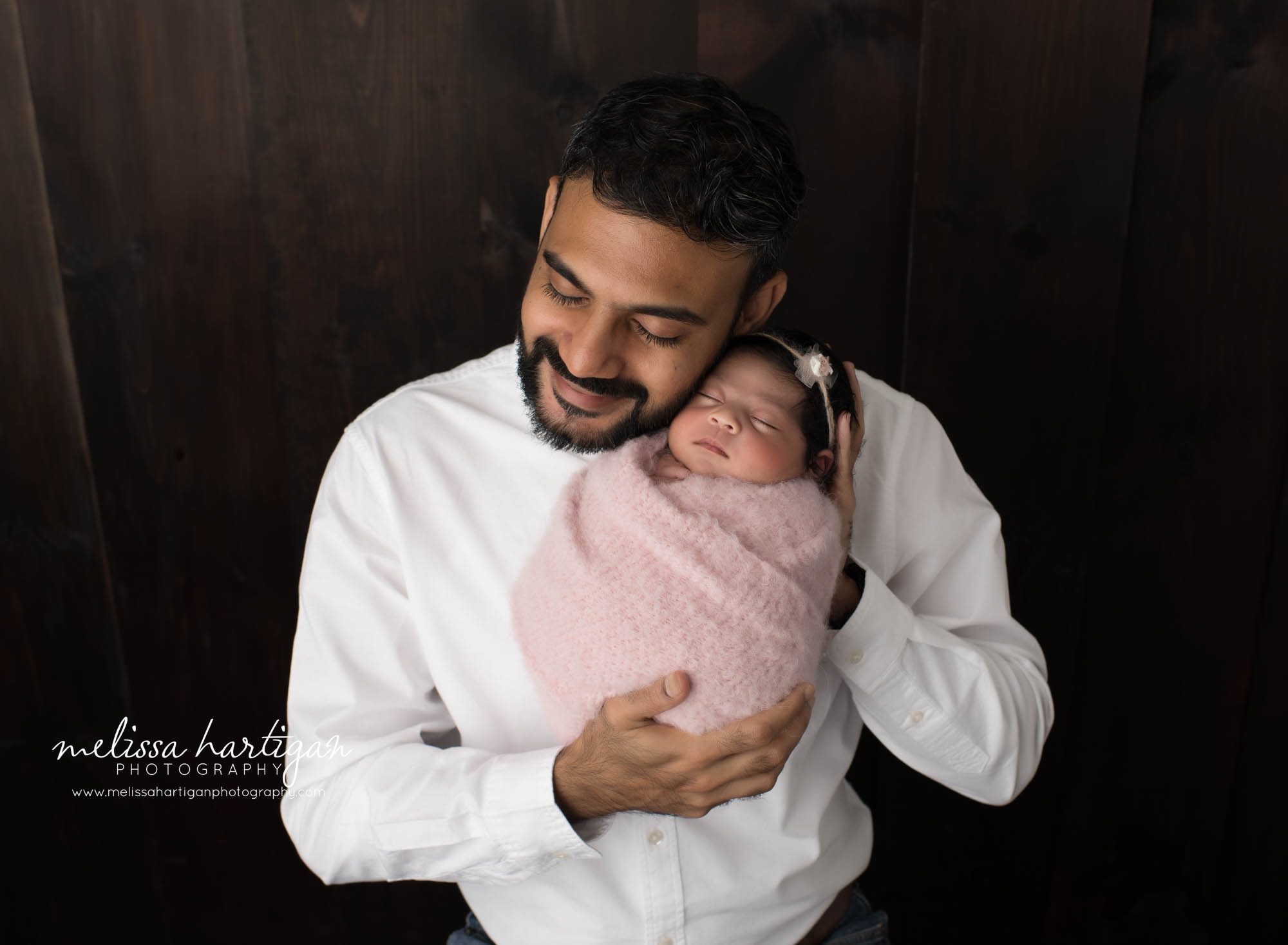 Dad holding newborn daughter in parents pose in baby photoshoot