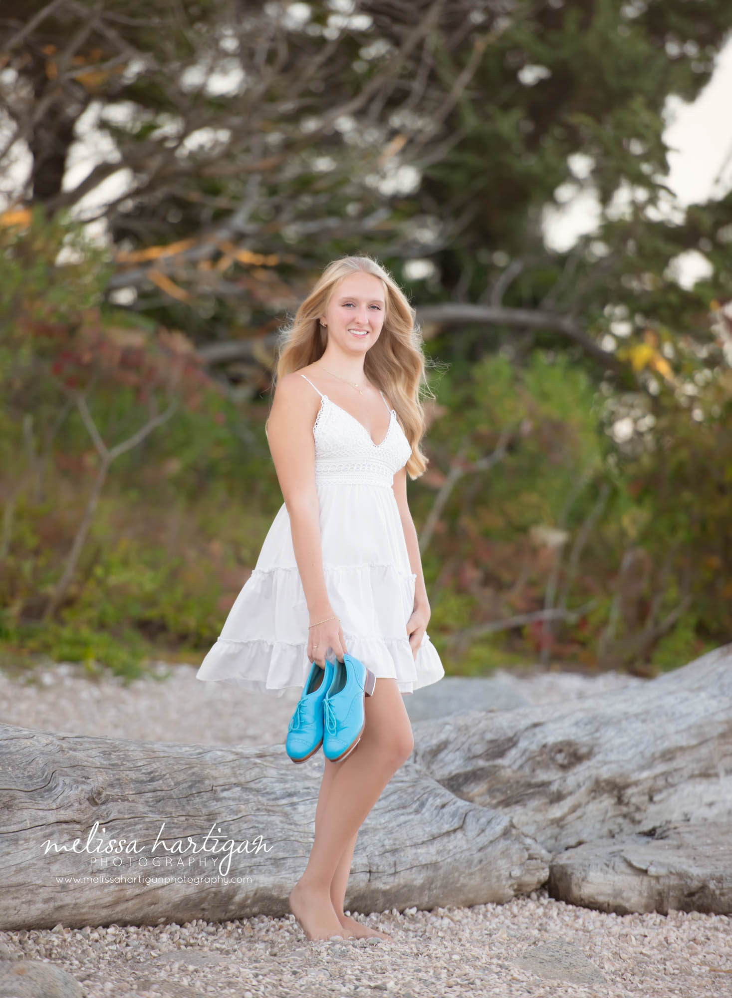 Girl standing on beach holding tap dance shoes