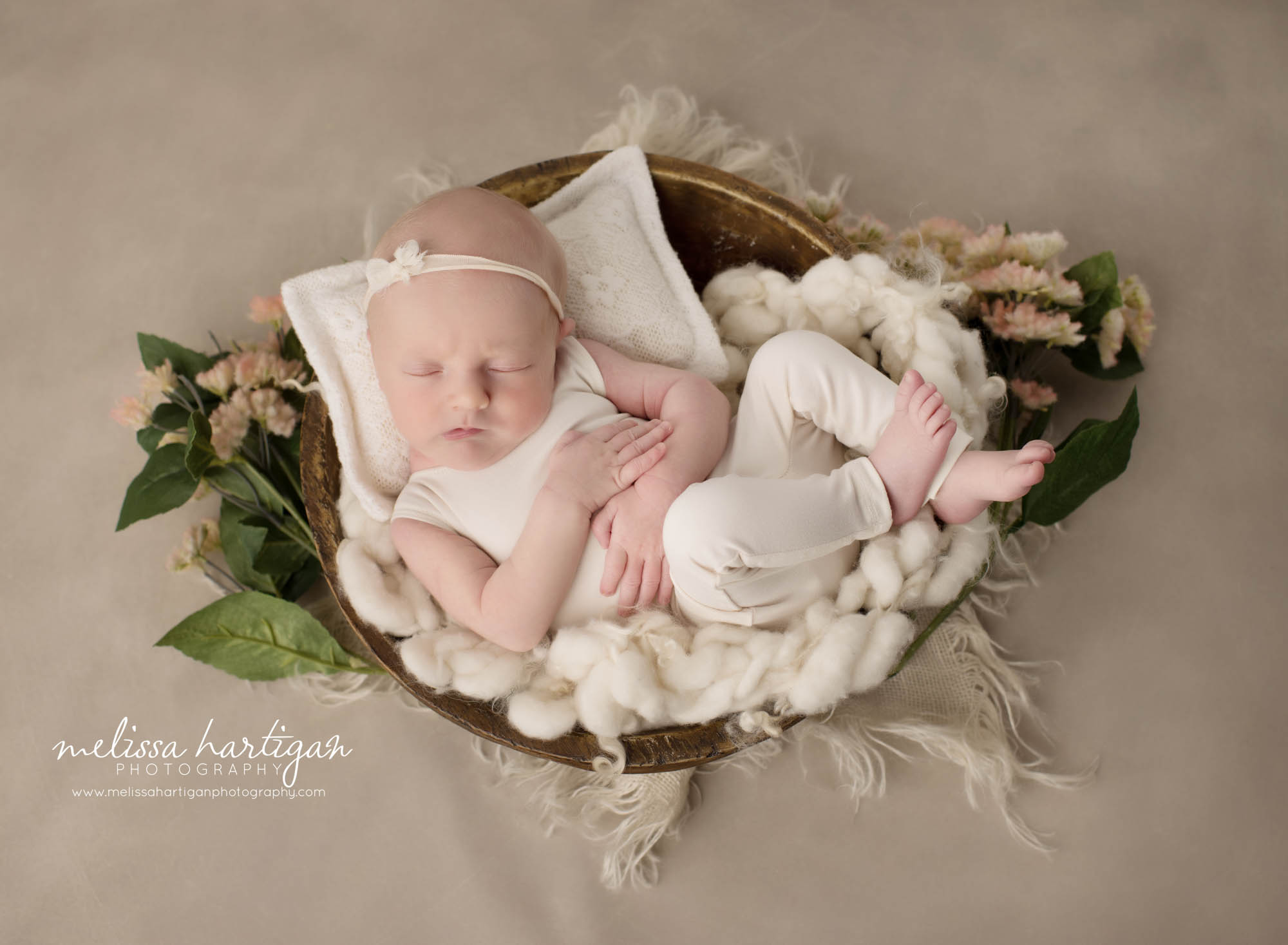 newborn baby girl posed in wooden bowl wearing newborn outfit