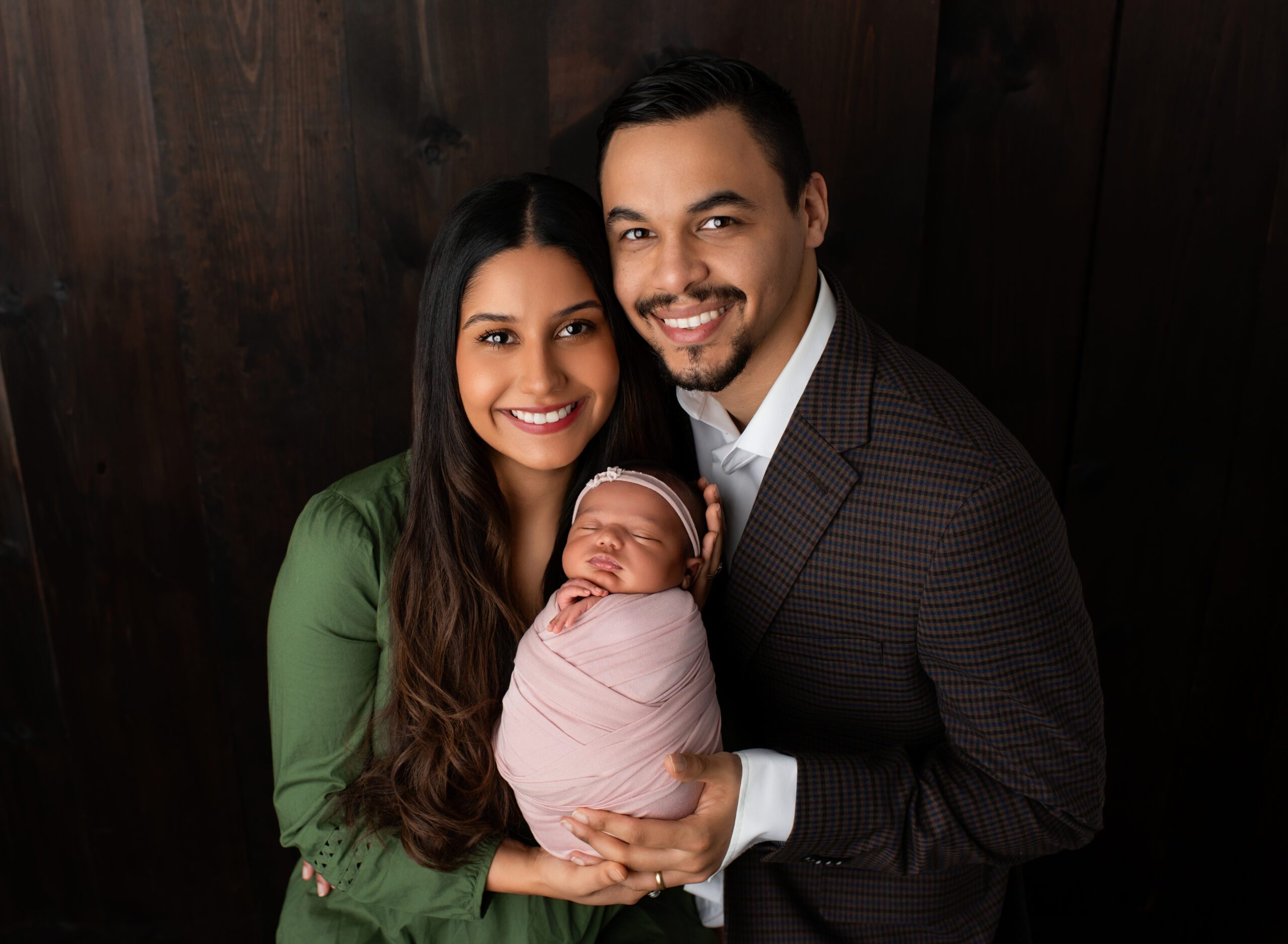 Mom dad and newborn daughter posed together for family pose