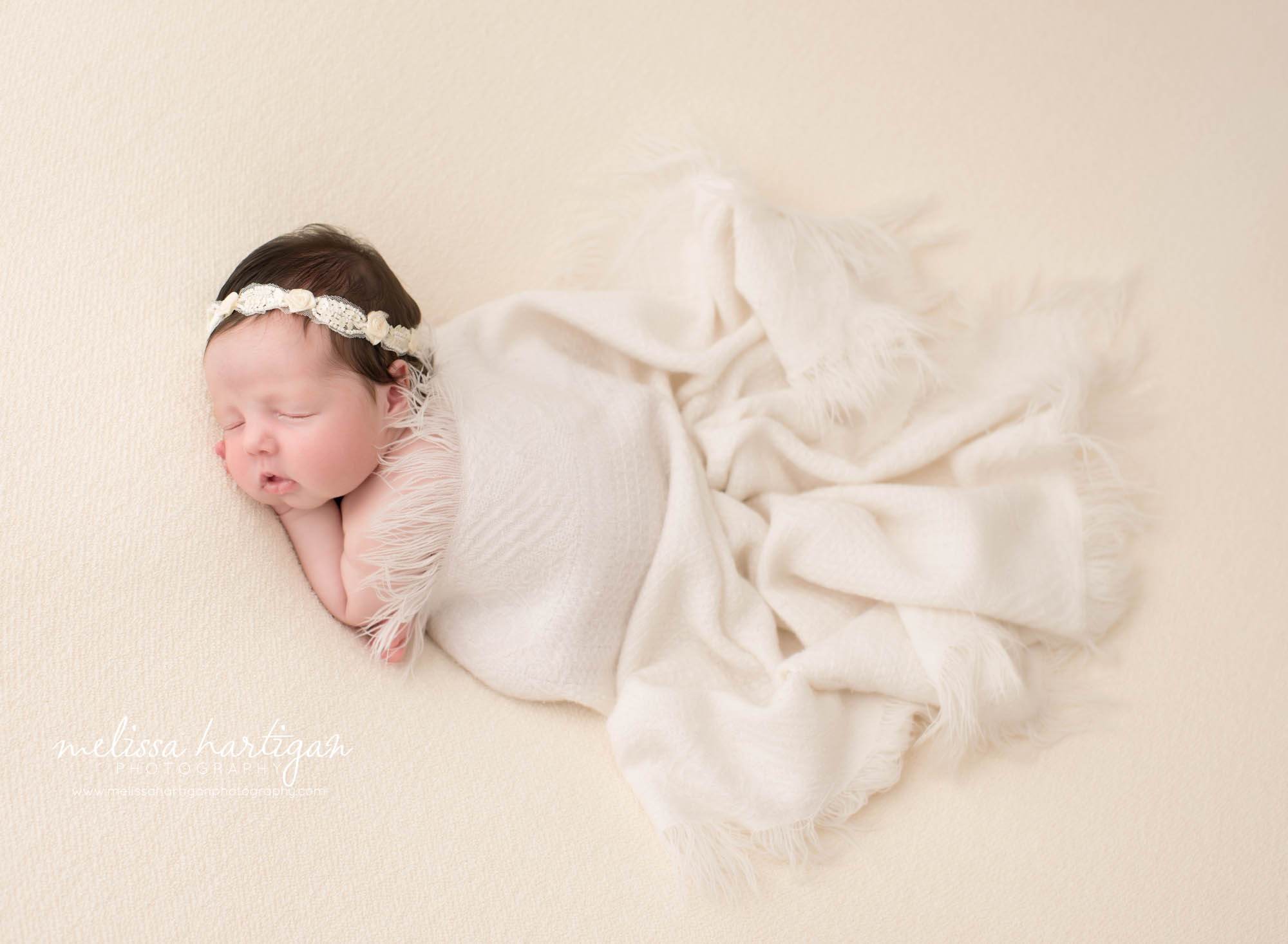 Newborn baby girl posed on tummy with cream baby blanket draped over her Newborn Photography Coventry CT