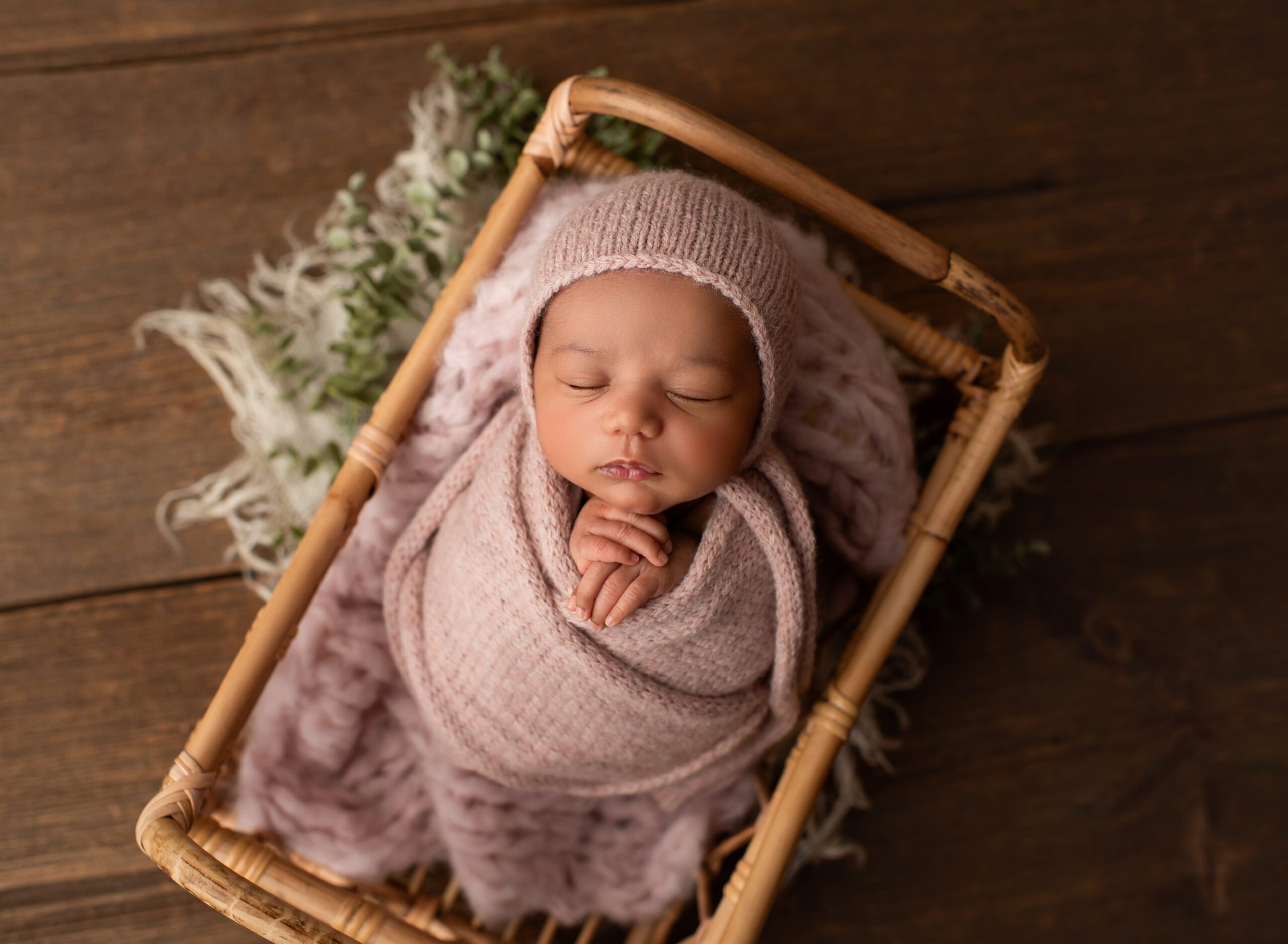 Newborn baby girl wrapped in pink wrap posed in basket wearing bonnet Newborn Photography Simsbury CT