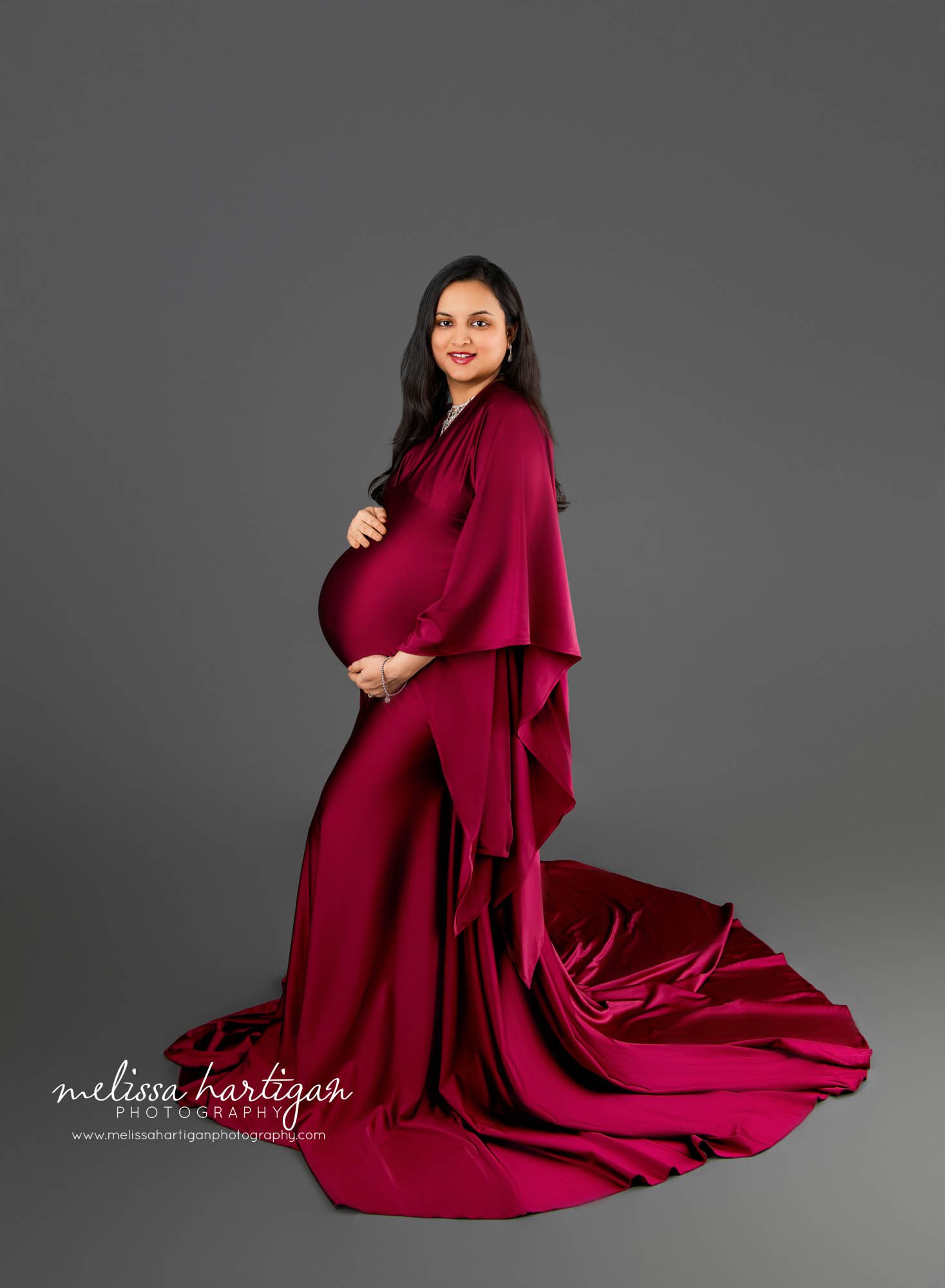 pregnant mom wearing long maroon dress in maternity studio photoshoot