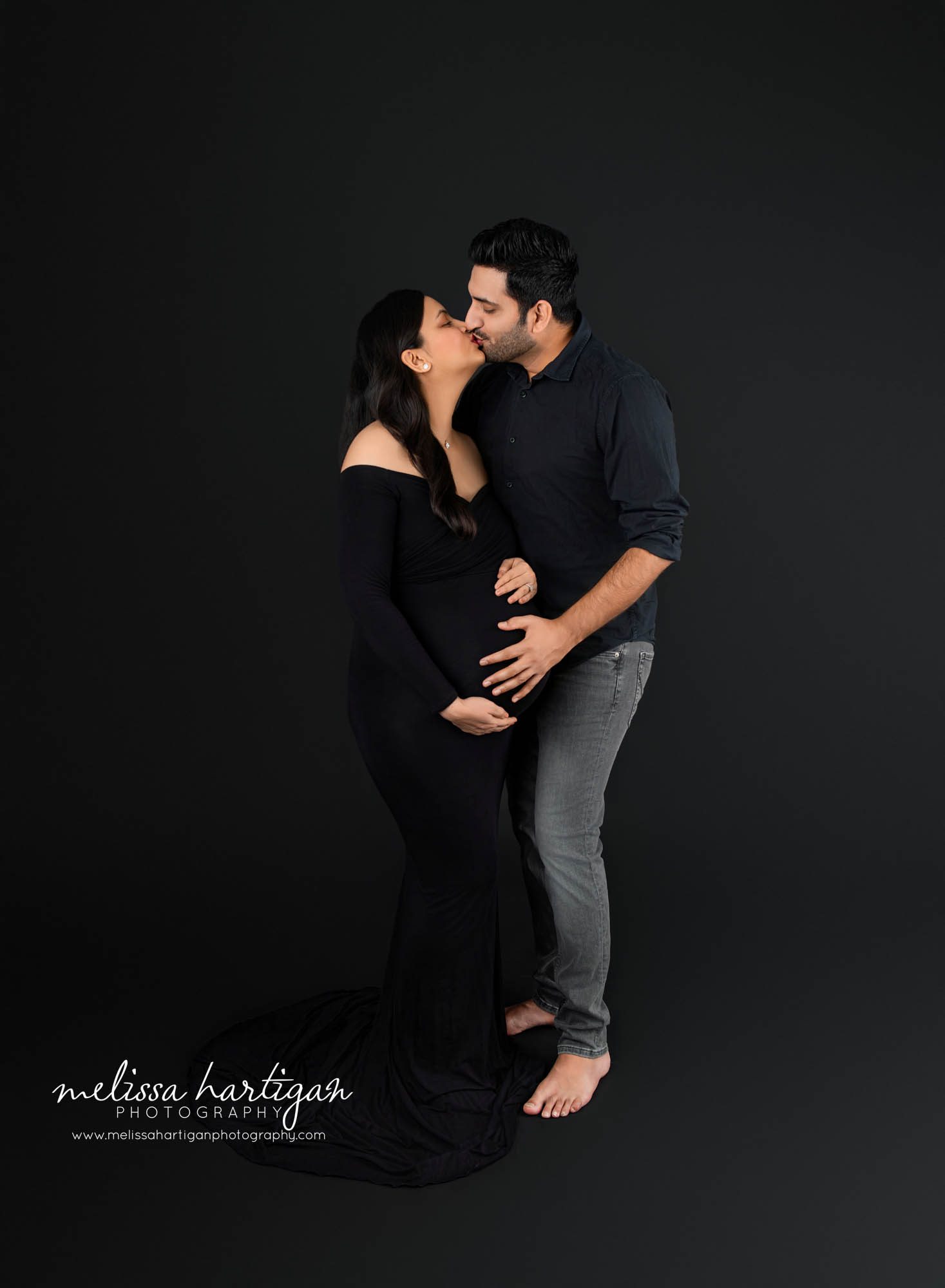 Couple standing kissing in maternity photoshoot