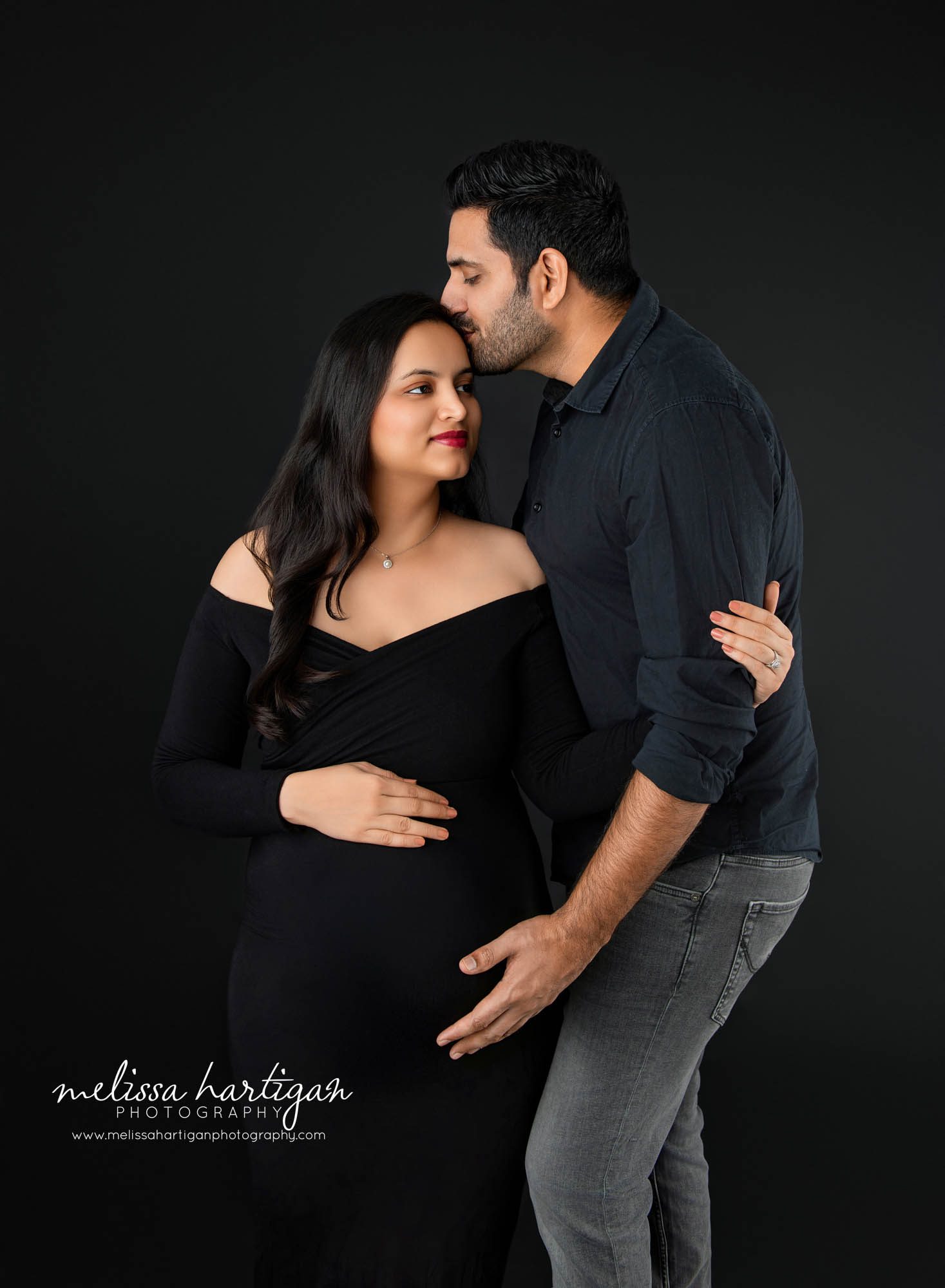 Dad-to-be giving mom kiss on forehead holding baby bump Maternity Photography South Windsor